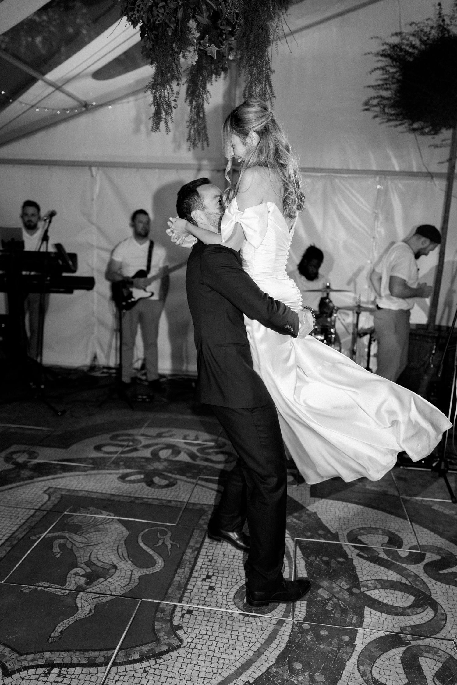 Wedding party dancing energetically on a decorative floor in black and white photography.