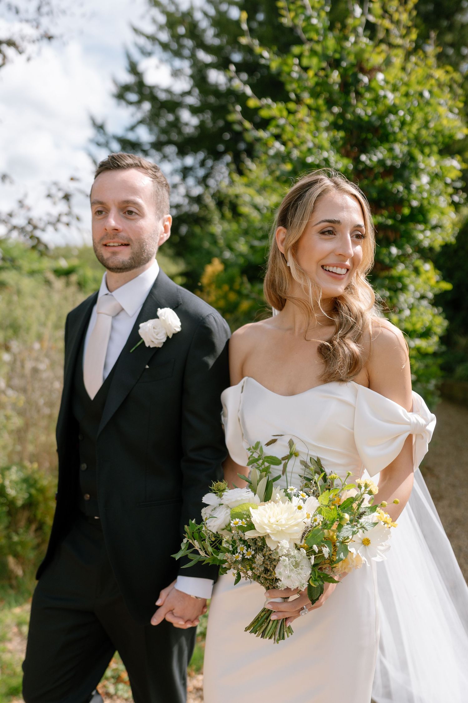 Joyful wedding couple sharing candid moments in sunny garden setting.