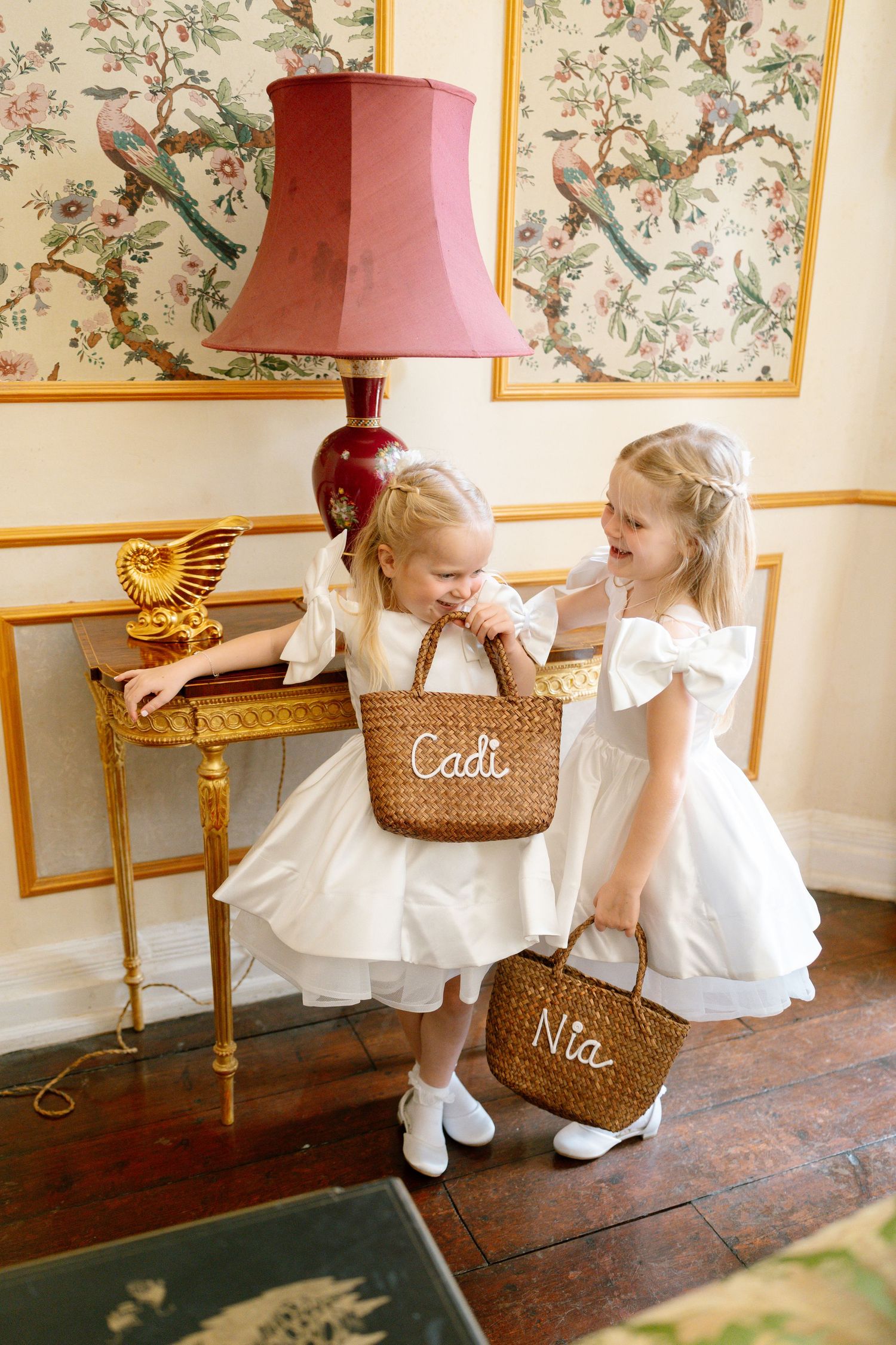 Children with wicker baskets explore a decorative room with floral wallpaper.