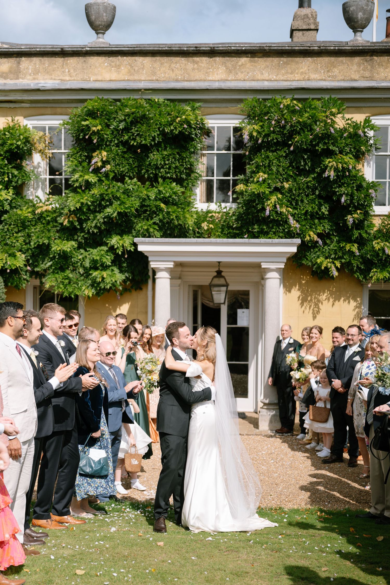 Guests throw confetti at the newlyweds outside a grand country house.