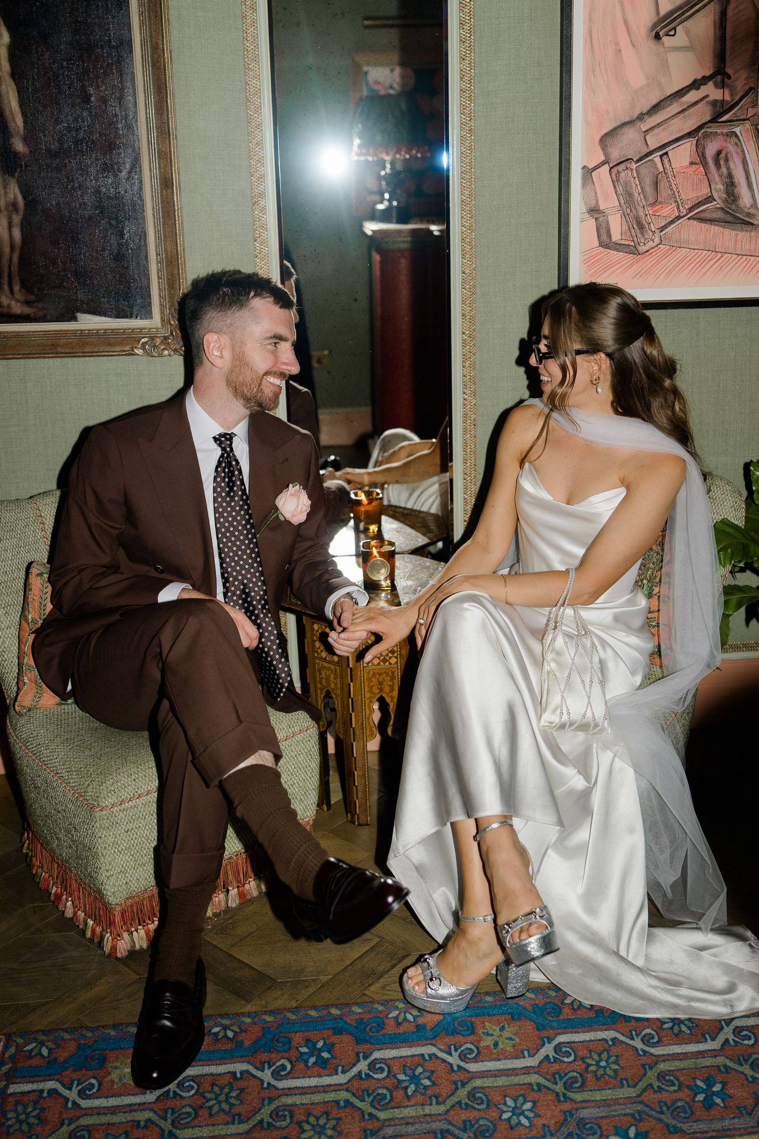 Bride and groom share a relaxed moment seated together in an elegantly decorated wedding venue.