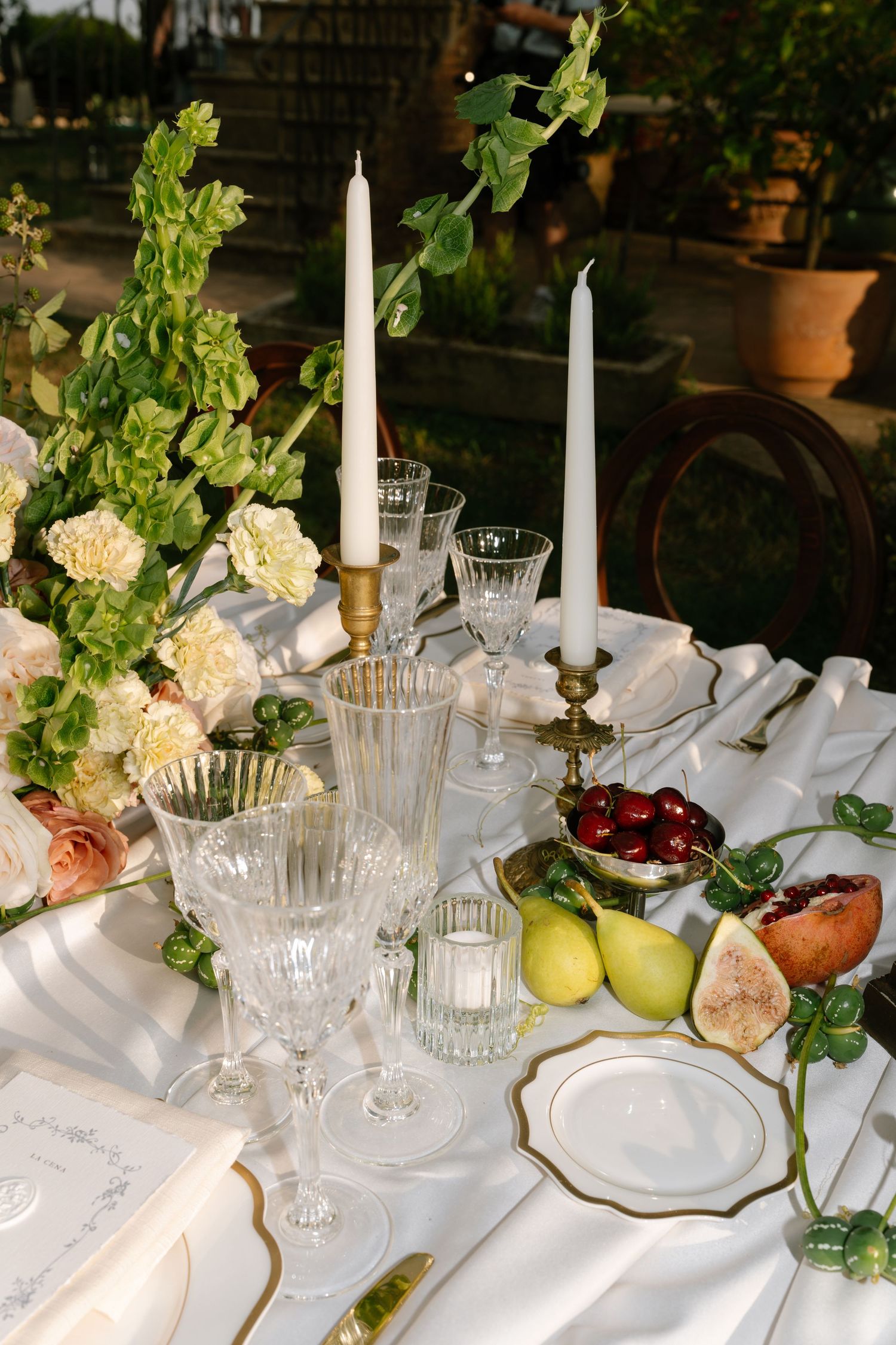 An elegant table setting with candles, glassware, and fresh fruit decorations.