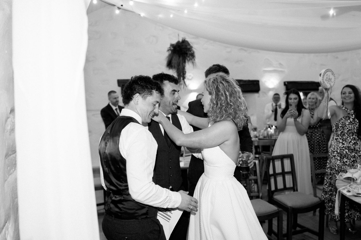 Black and white photo of dancing at a wedding reception with white draped decor.