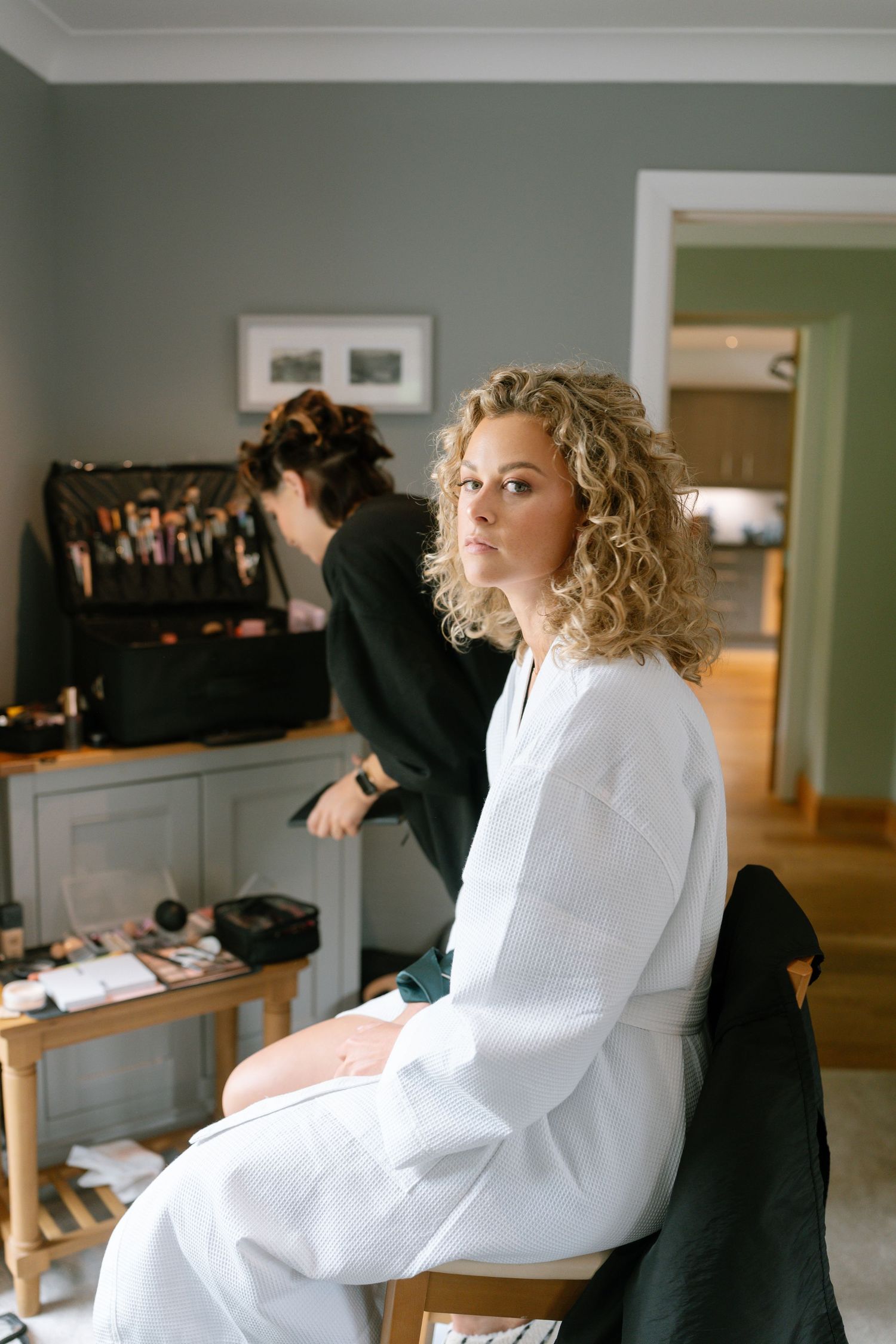 A person in a white robe sitting in a modern room during wedding preparations.