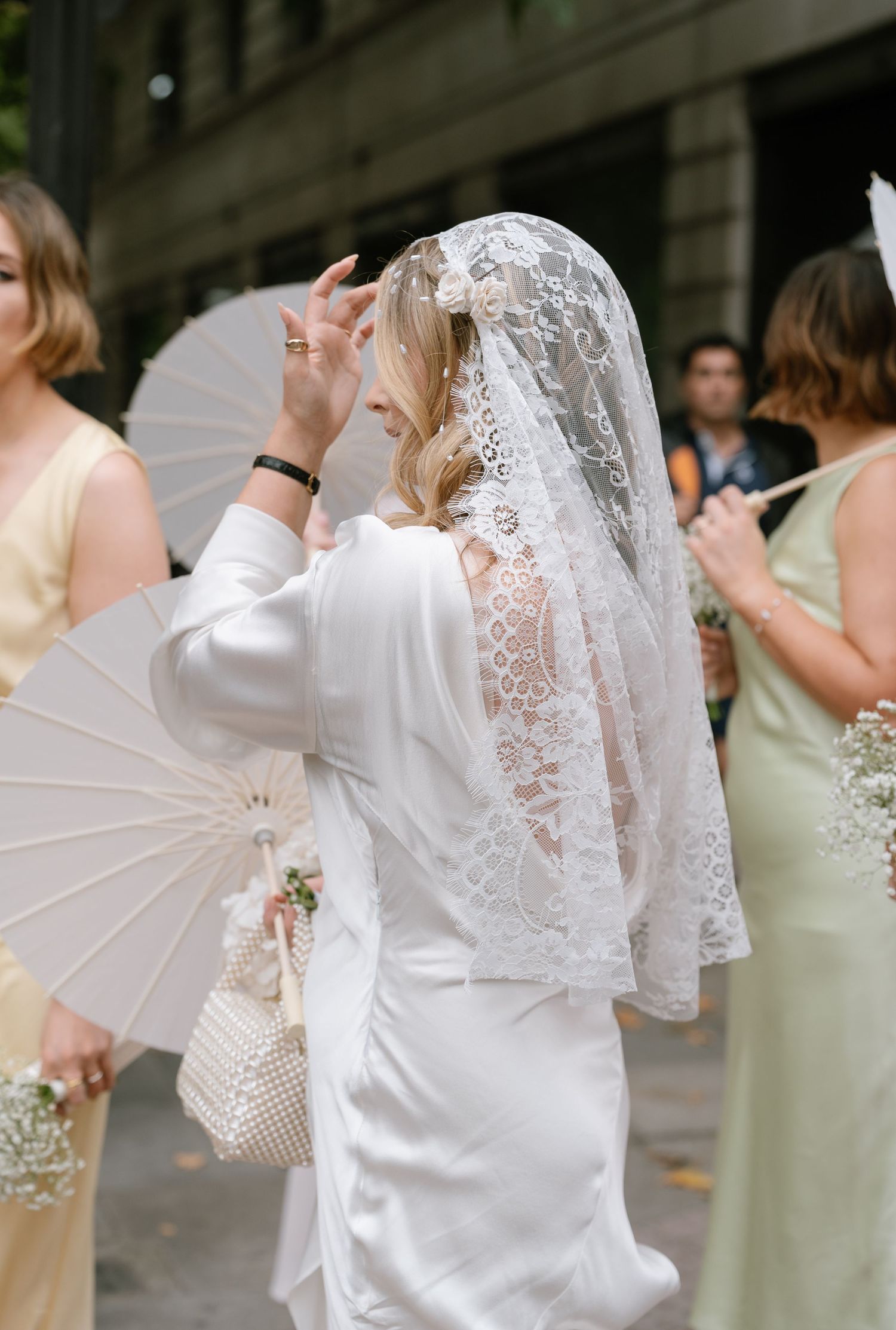 Wedding party members in white attire and sage green dresses walking together.