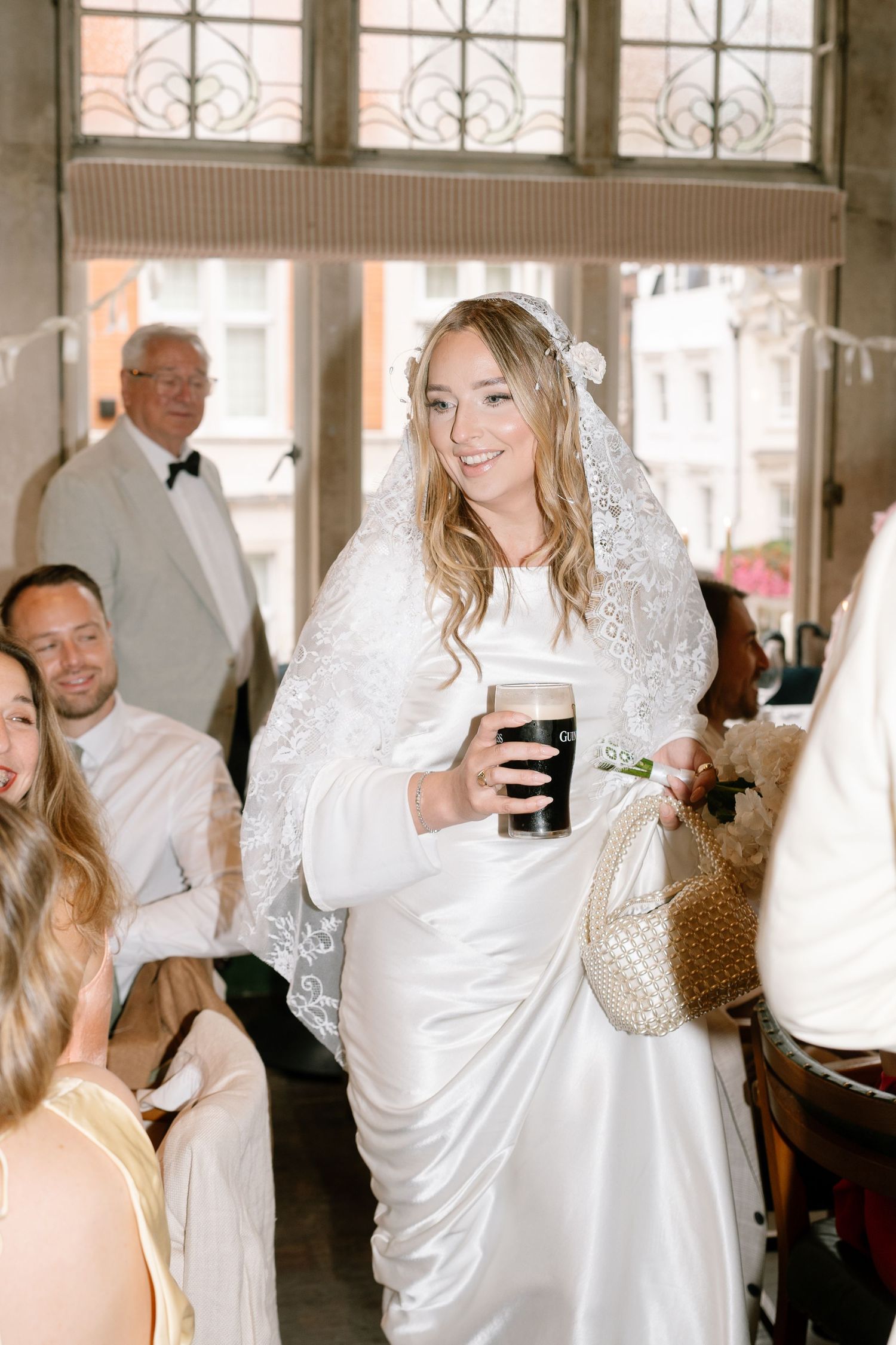 Wedding celebration inside a bright venue with guests in white attire.