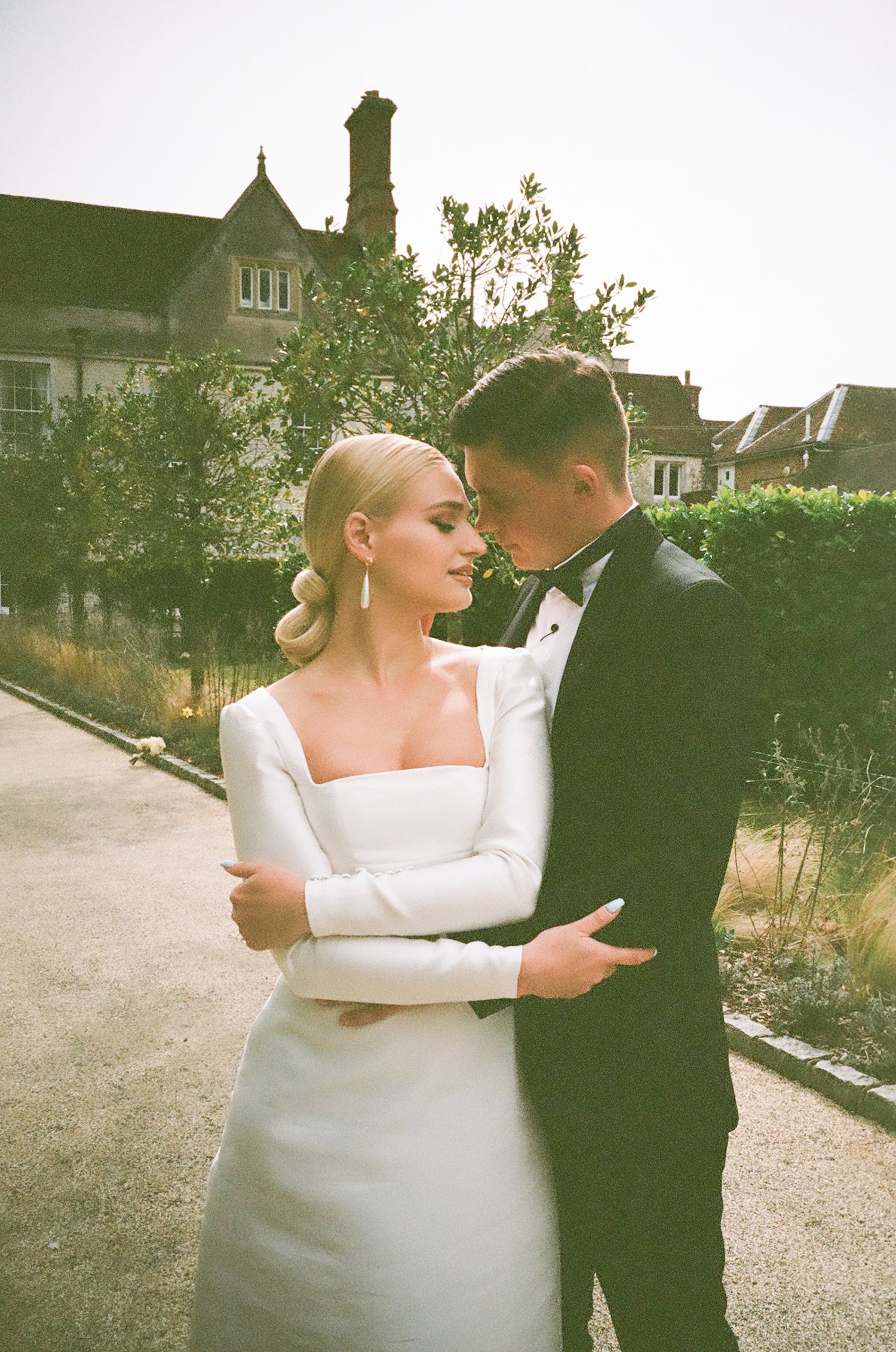 A couple in wedding attire shares an intimate dance moment outdoors with vintage-style photography effects.