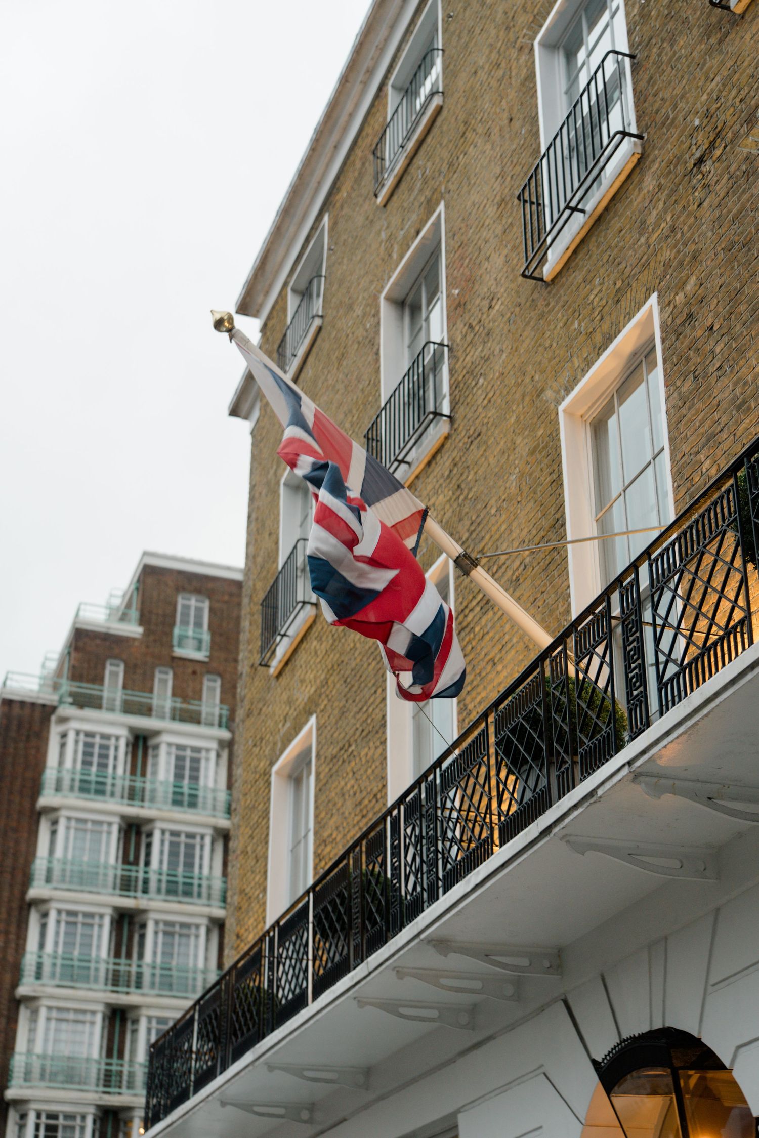 Union Jack flag flies from a brick building balcony in London.