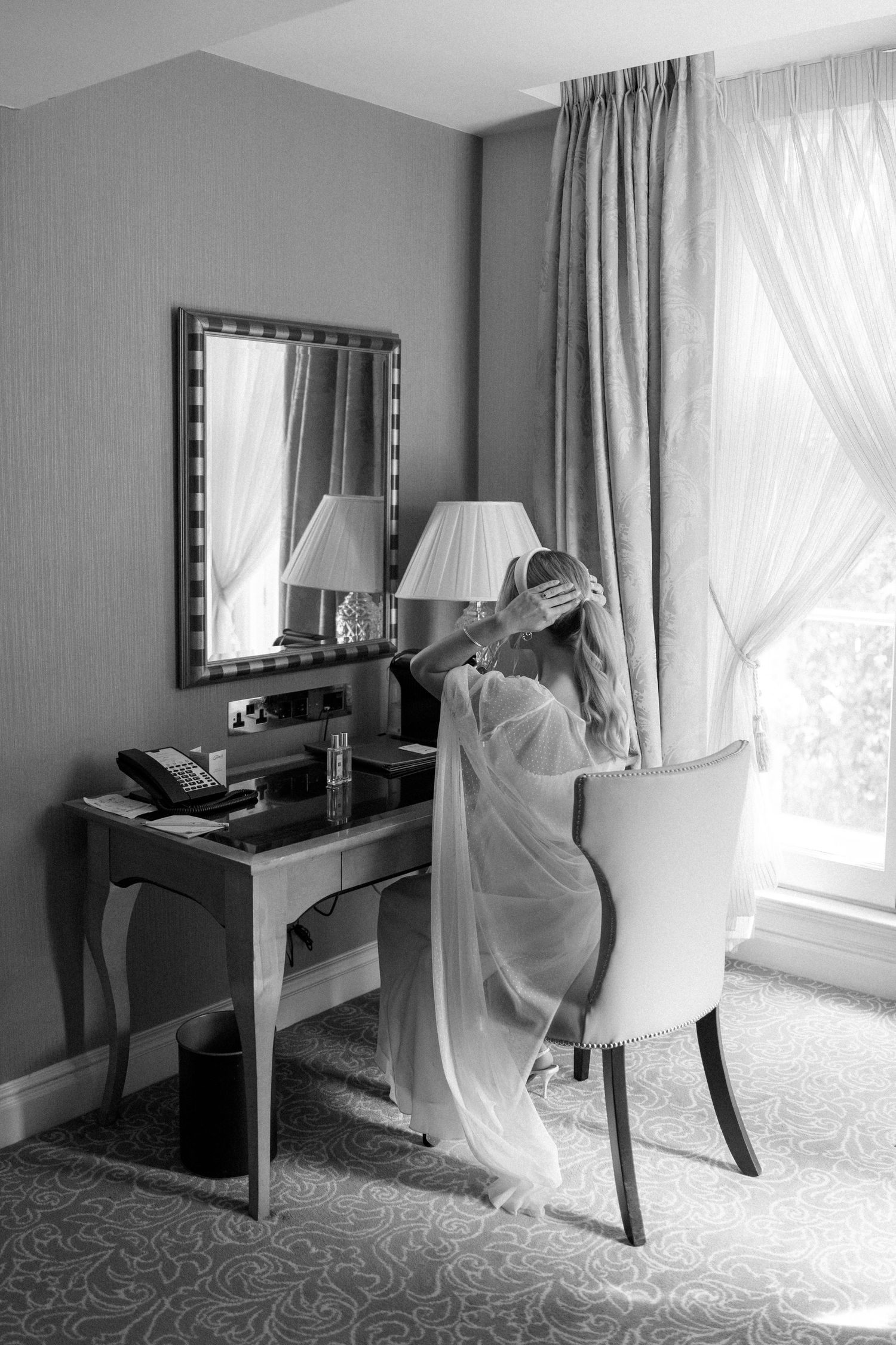Wedding preparation scene with vanity table and flowing curtains in elegant hotel room.