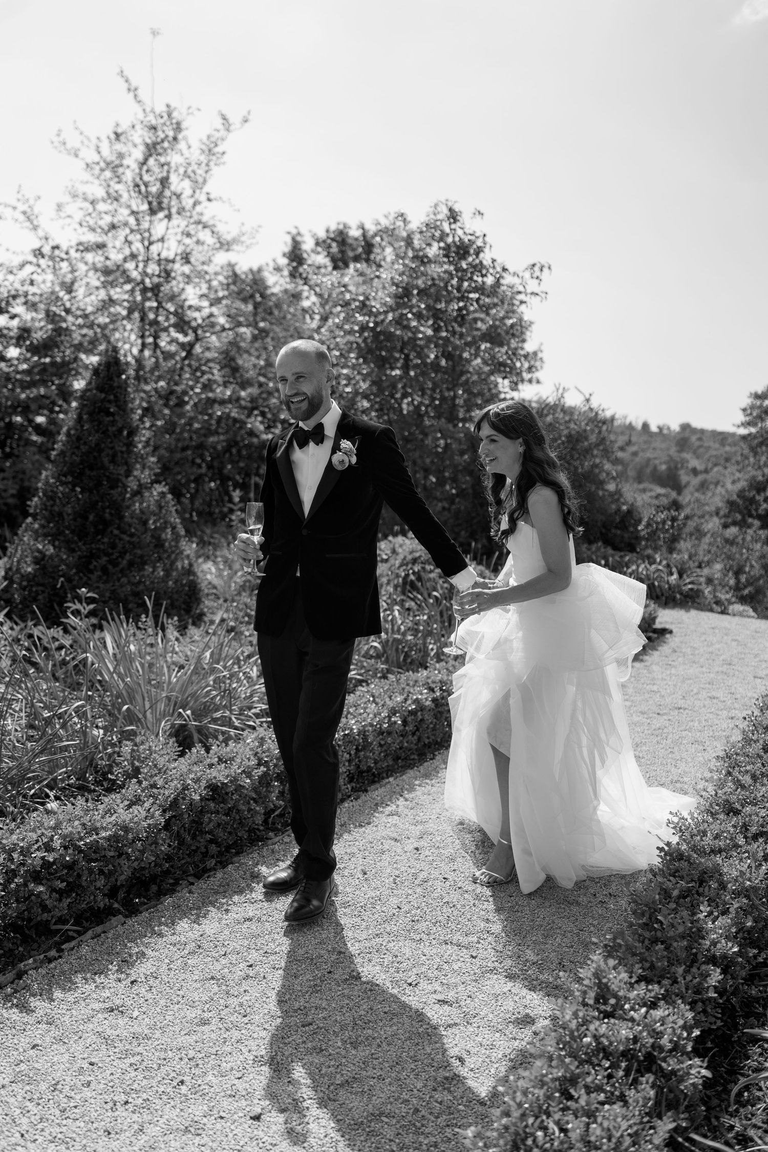 A black and white wedding photo sequence showing a couple walking through a scenic garden path.