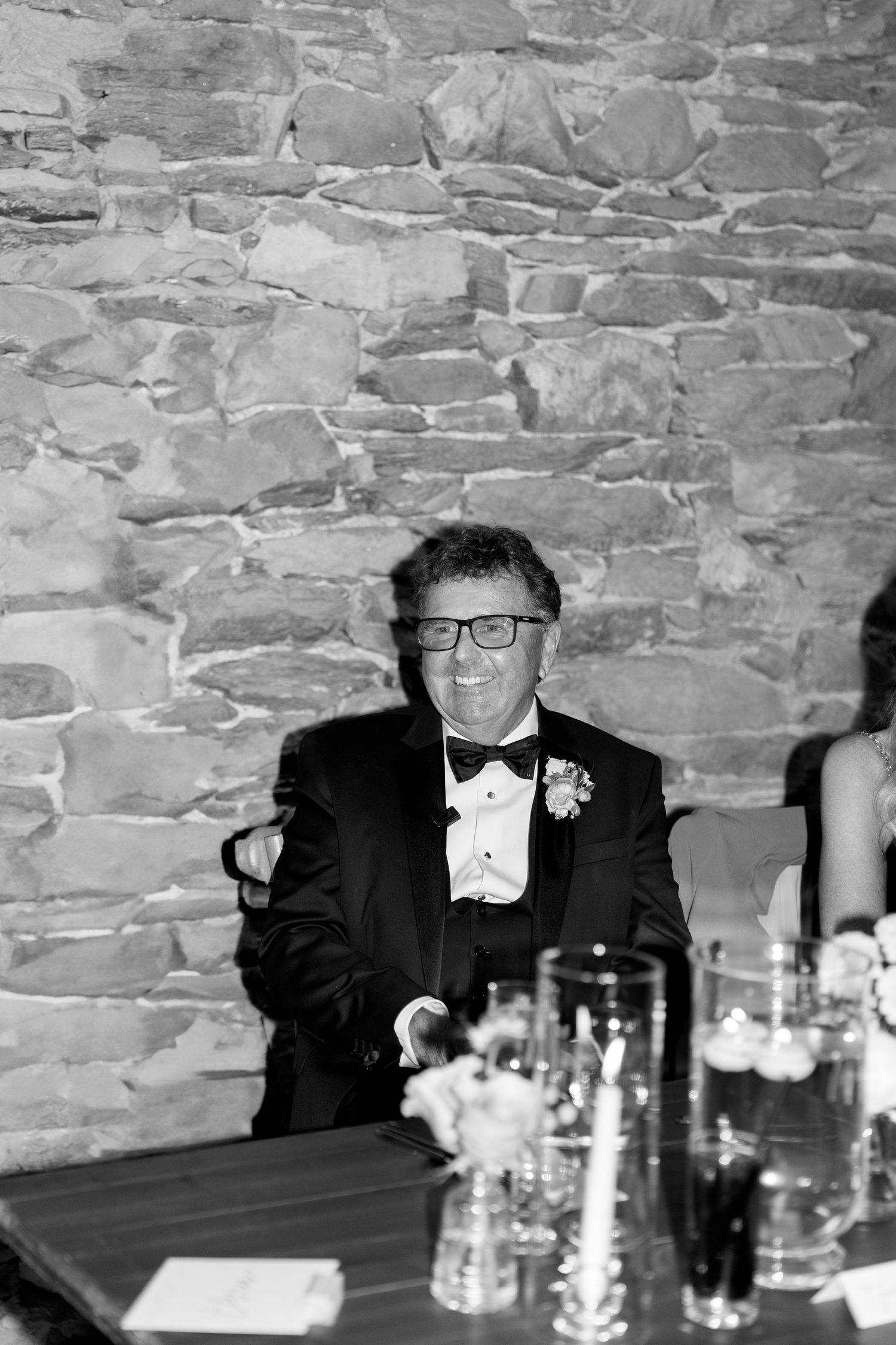 Wedding reception guests laughing at formal dinner table.
