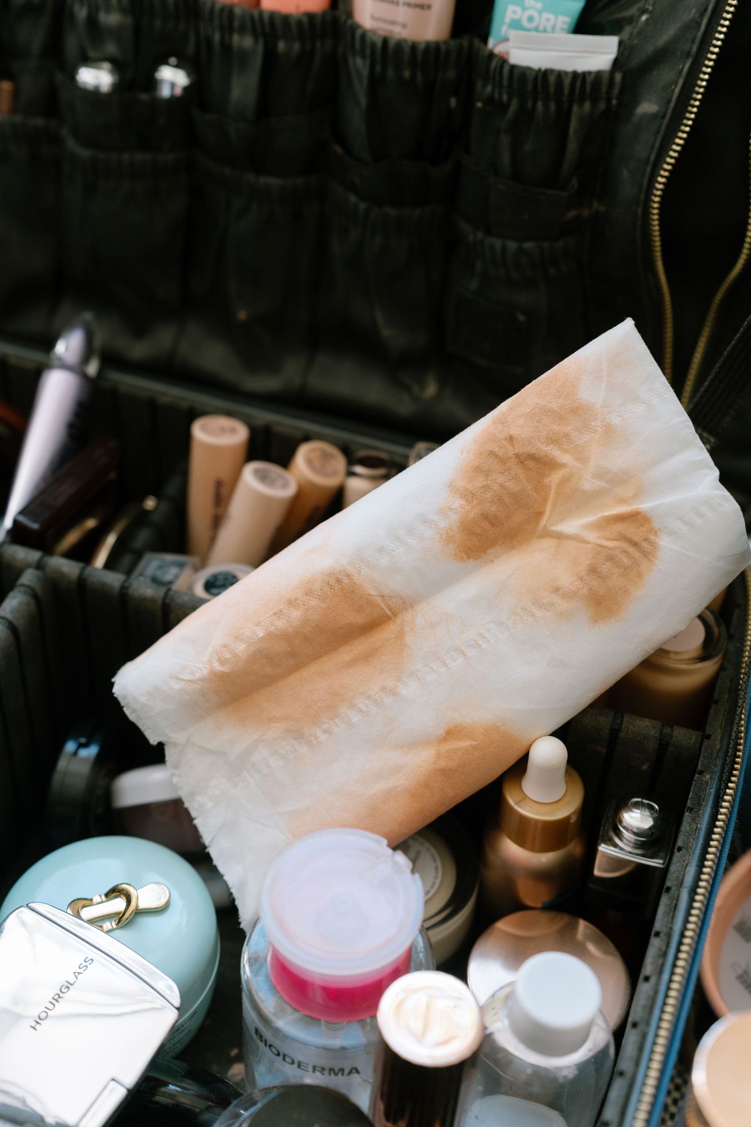 Makeup products and tissues arranged on a dark surface with metallic details.