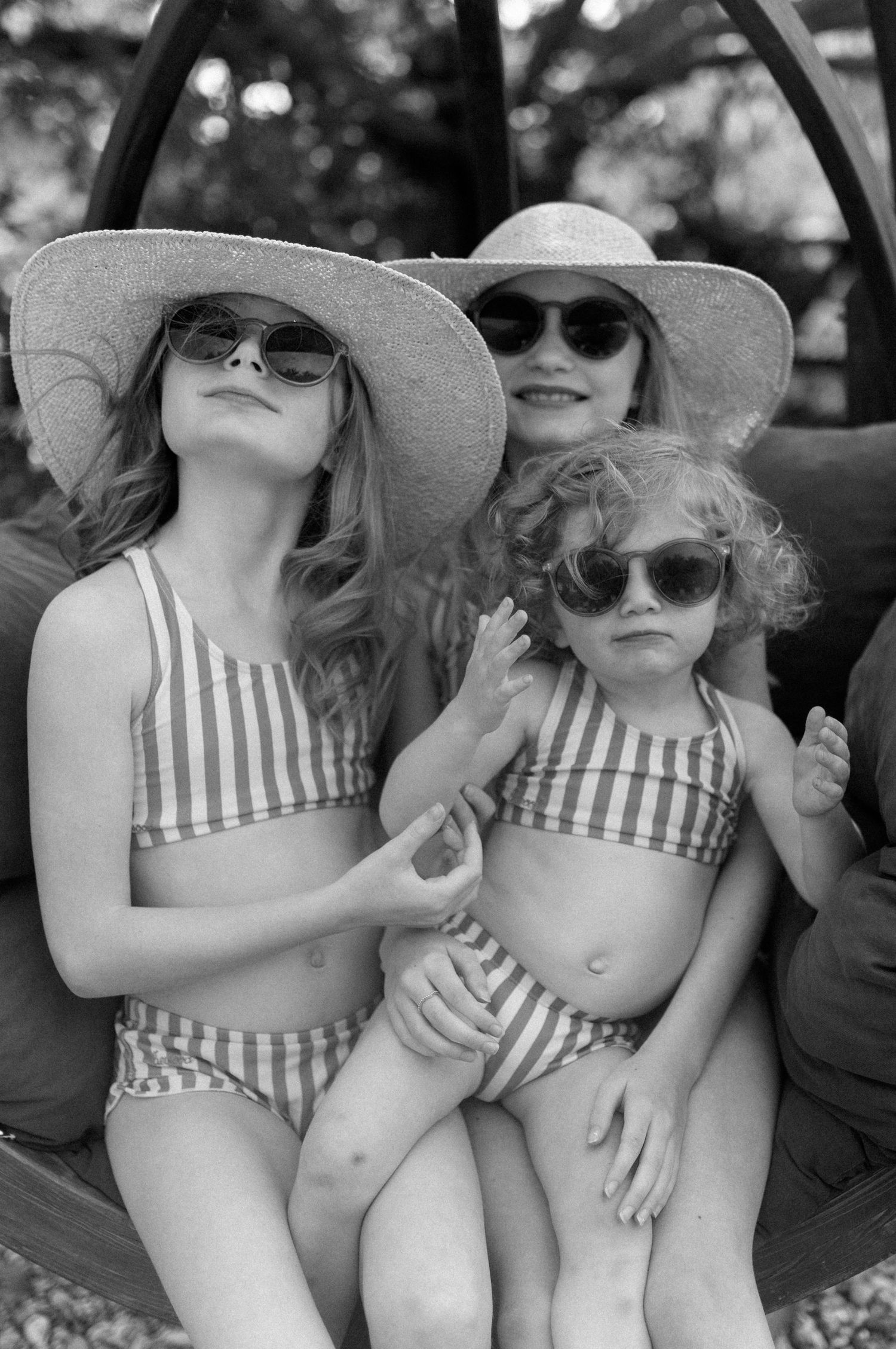 Kids wearing striped swimsuits and sun hats lounging together in black and white.