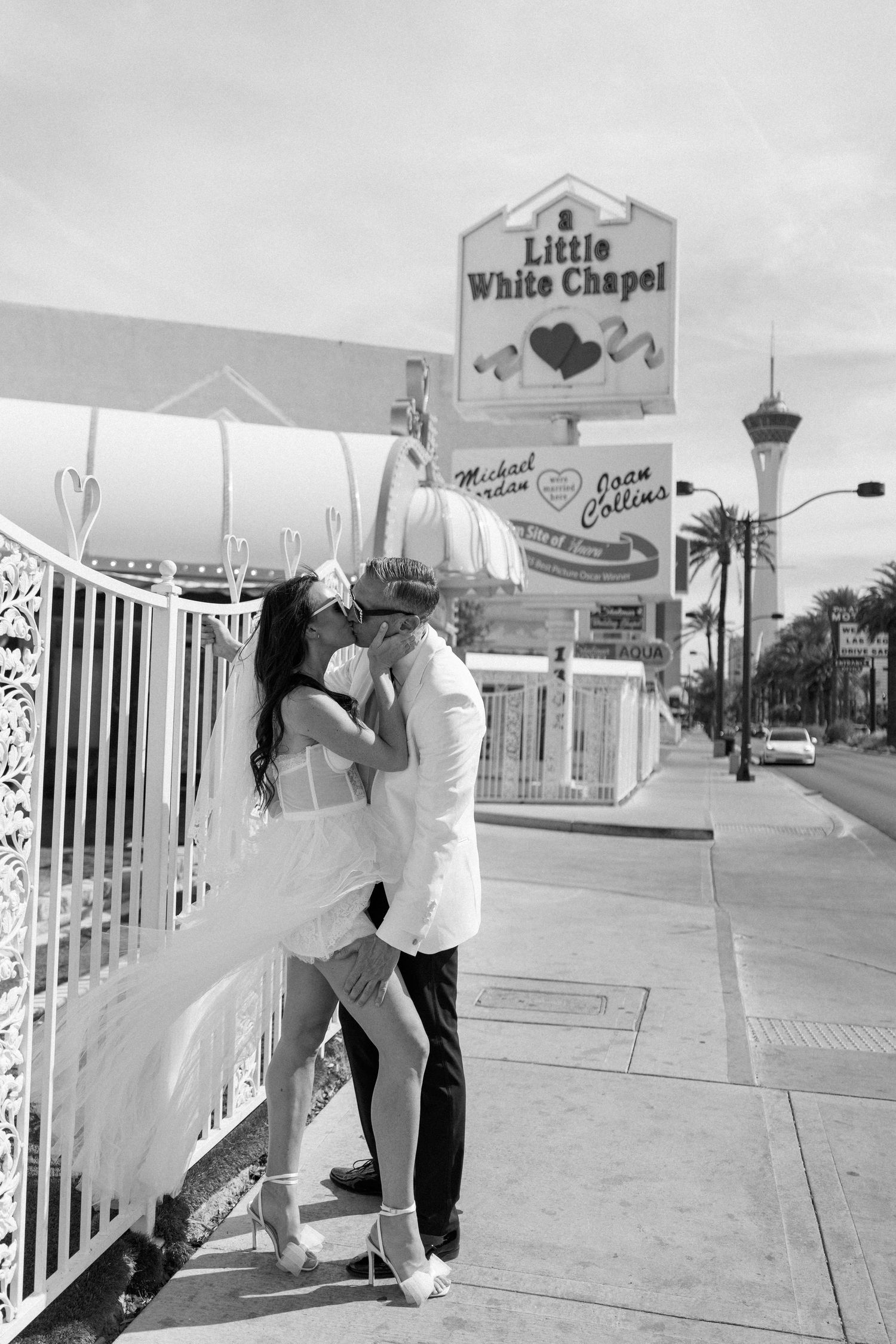 Bride and groom perform dance moves against white chapel fence in Las Vegas.