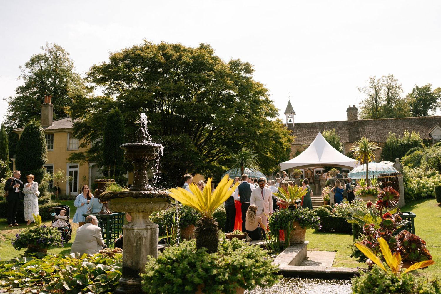 Panoramic view of an elegant outdoor wedding reception with white tents and landscaped gardens.