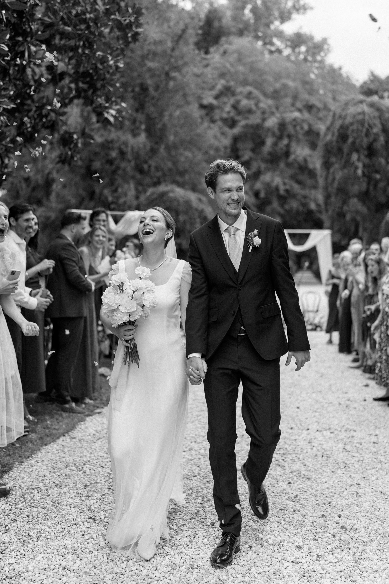 A black and white photo captures a couple's pure joy as they walk down the aisle after their ceremony.