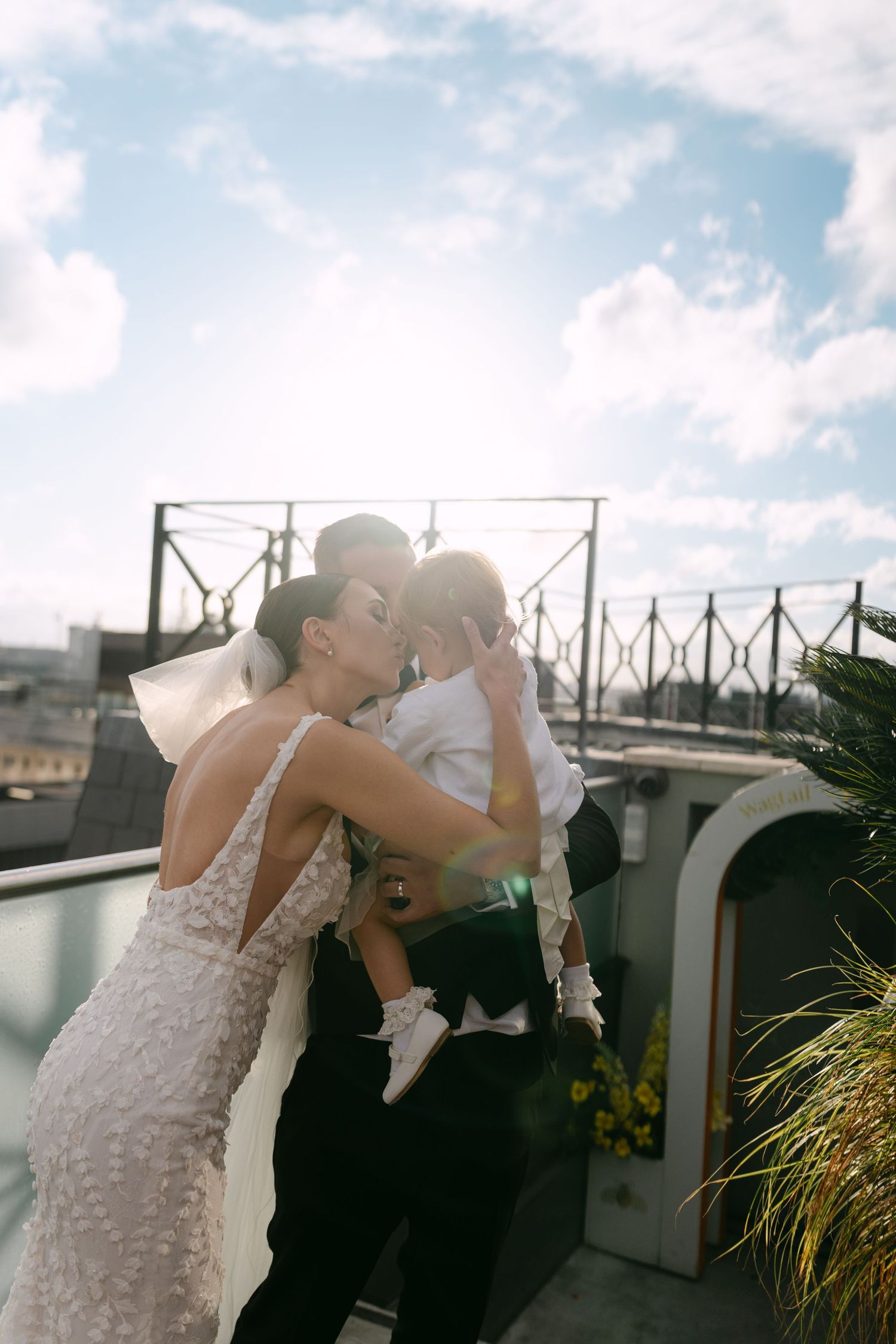 A joyful moment between newlyweds and their baby on a rooftop terrace.