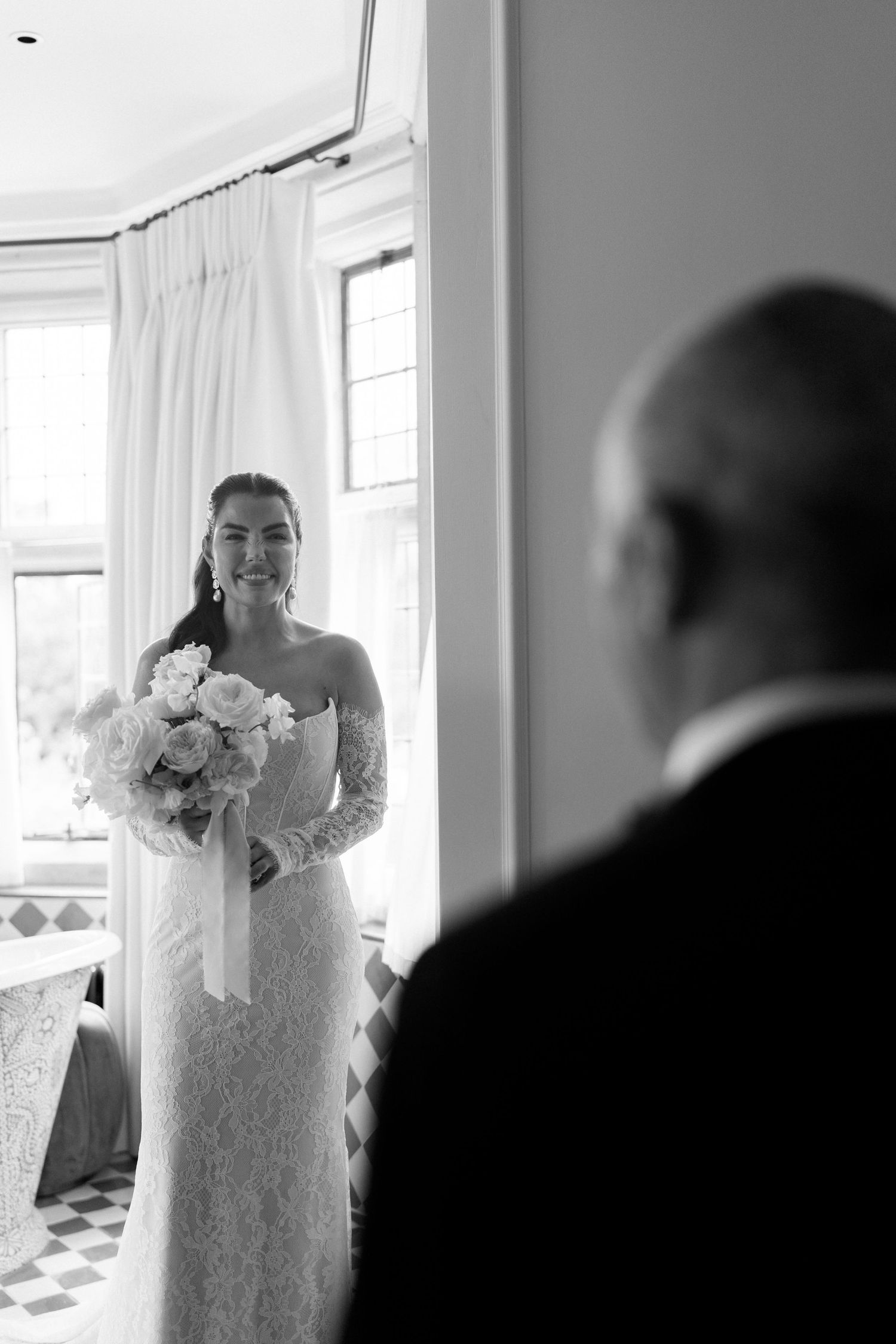 Emotional father seeing bride daughter for the first time in lace wedding dress, black and white photo.
