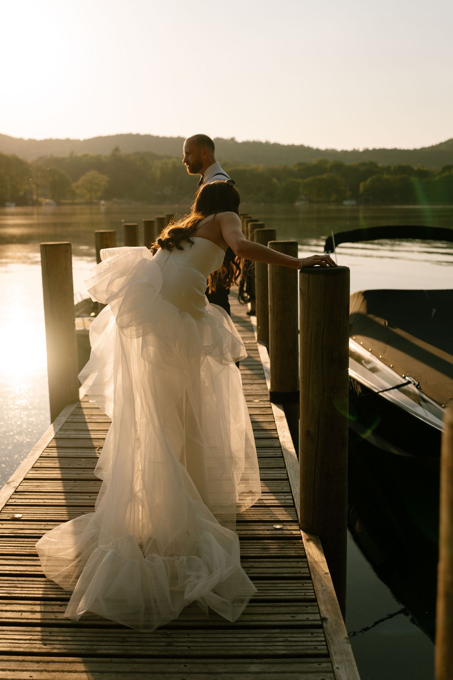 Sunset silhouette on a wooden dock with flowing white dress.