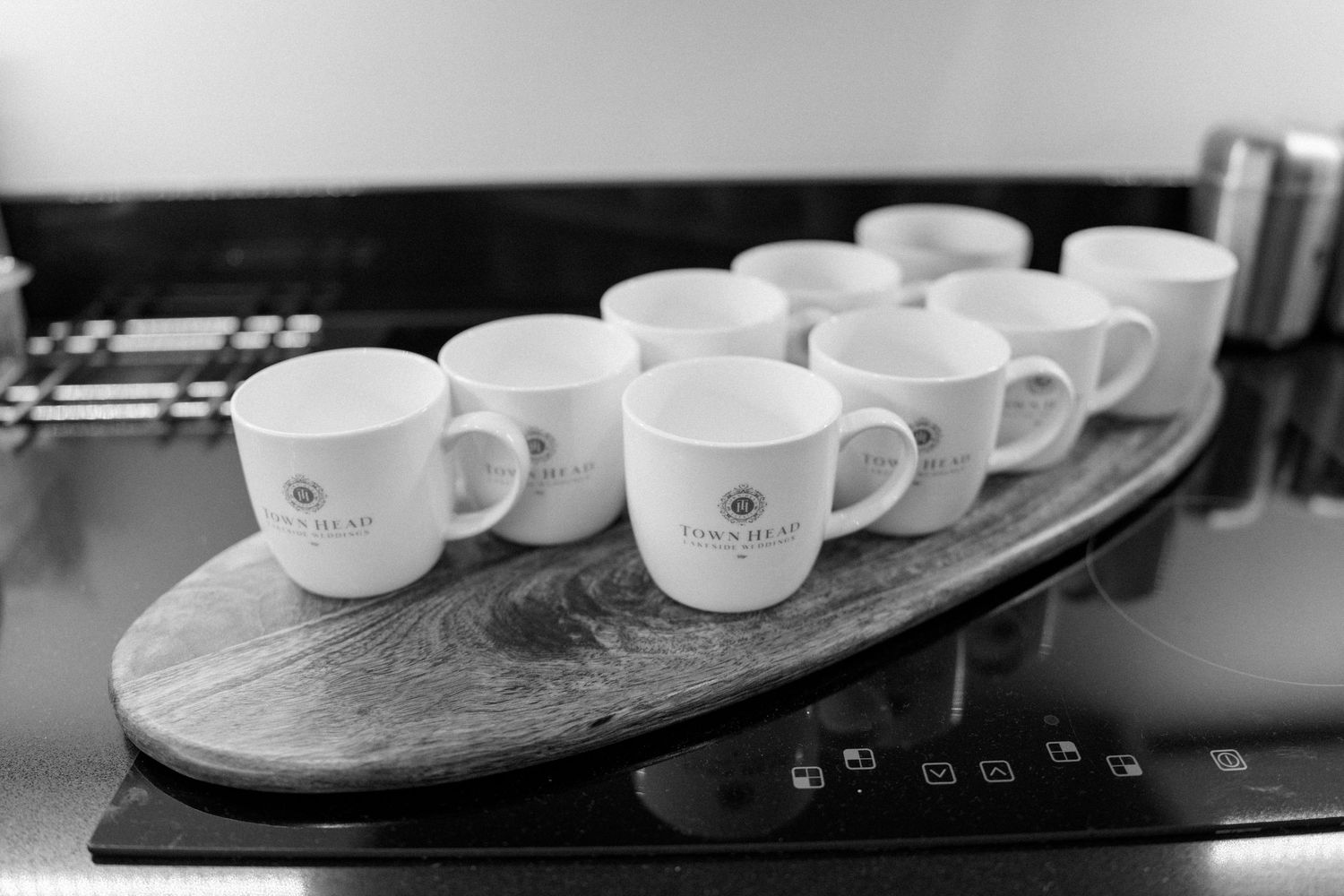 Row of white coffee cups arranged on a dark surface.
