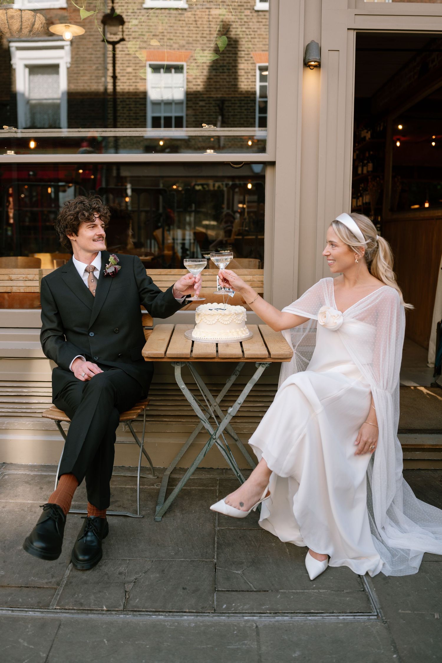 Wedding couple relaxing at outdoor cafe tables after their ceremony.