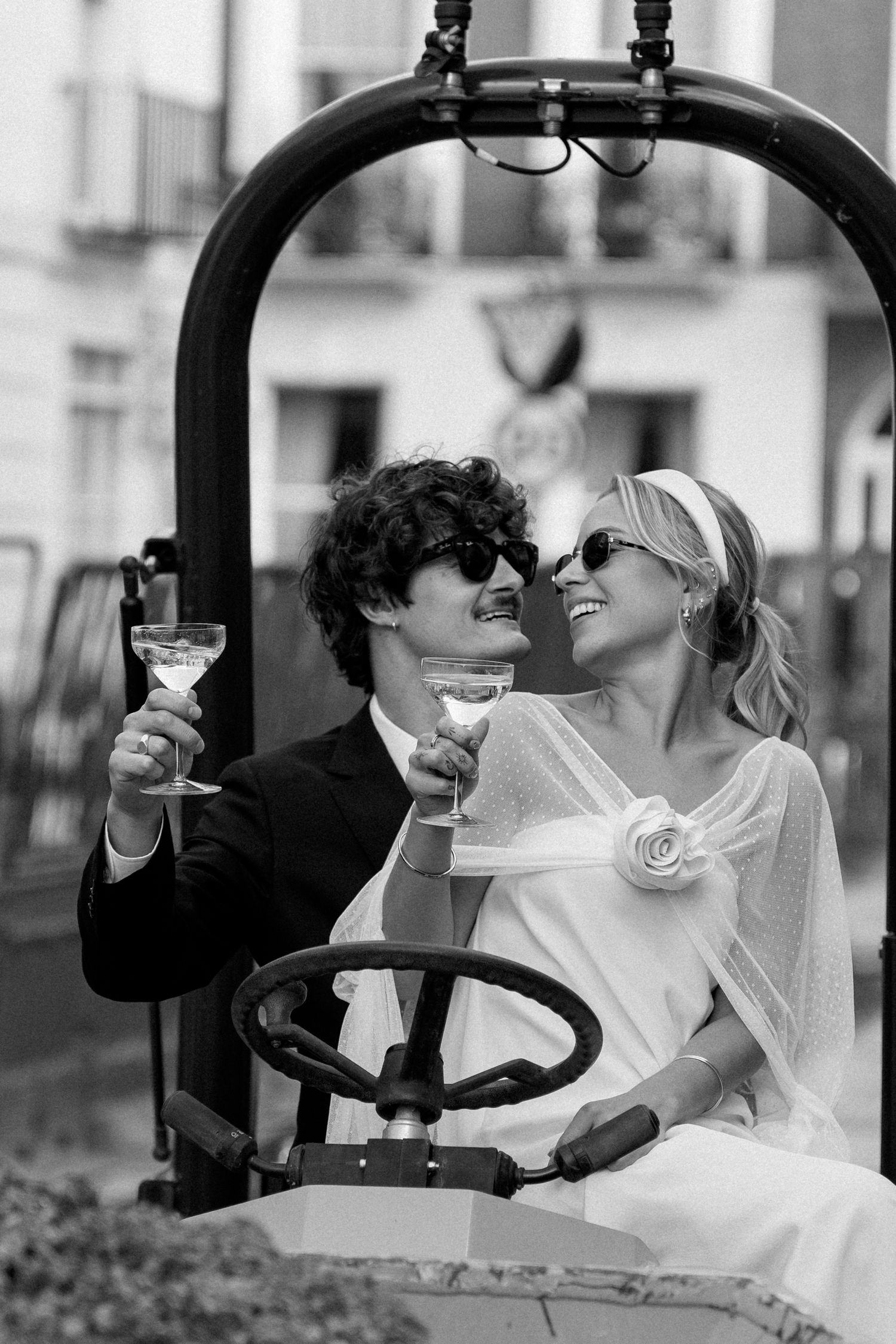 Newlyweds share an intimate moment while seated in a yellow construction vehicle.