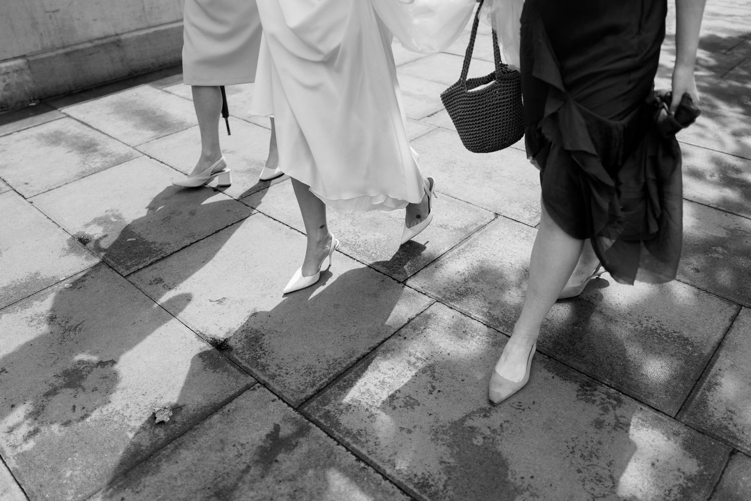 Artistic black and white series showing feet and dress movement across wet pavement.