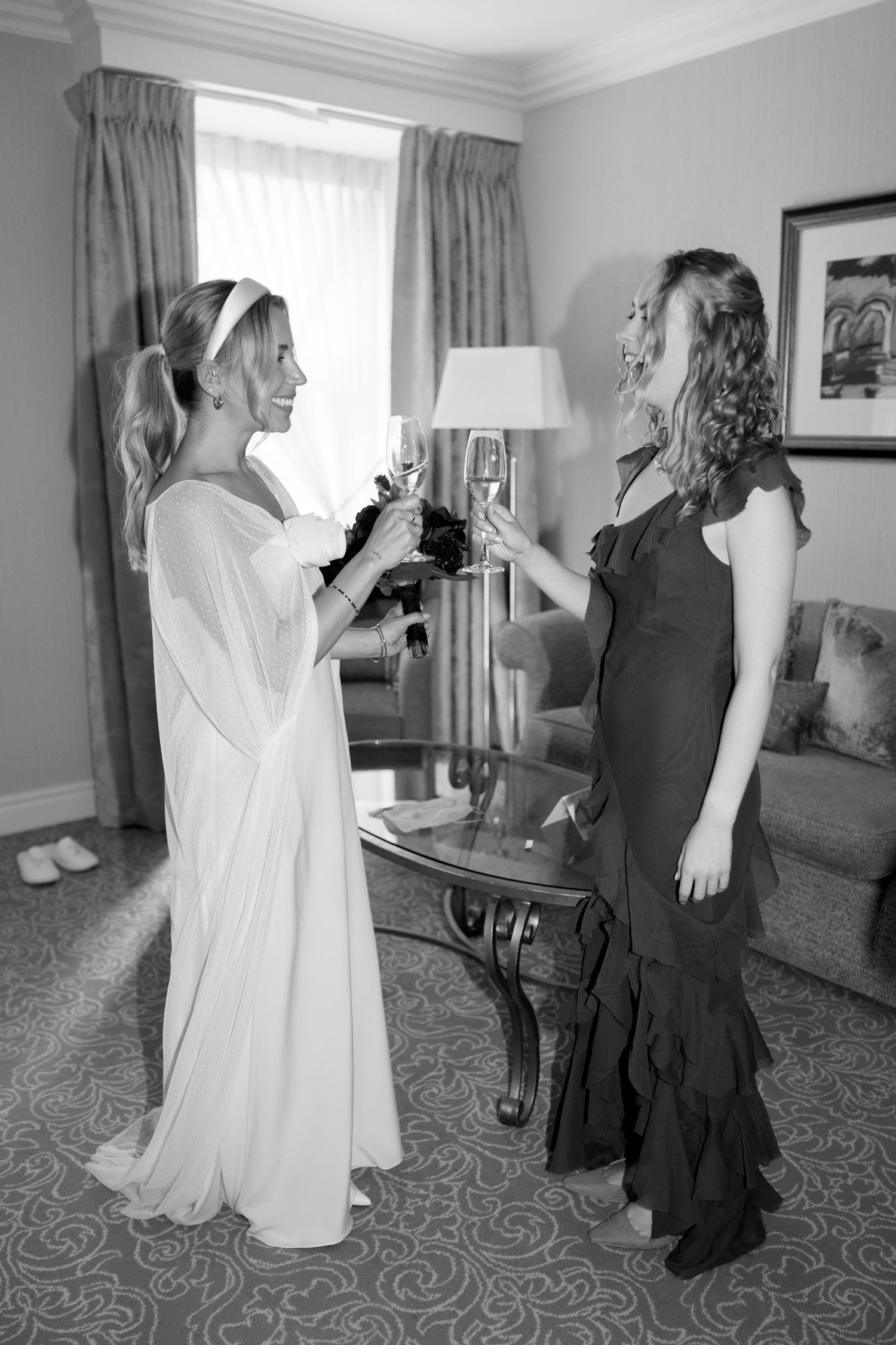 Wedding party in black and white preparing in hotel room with patterned carpet.