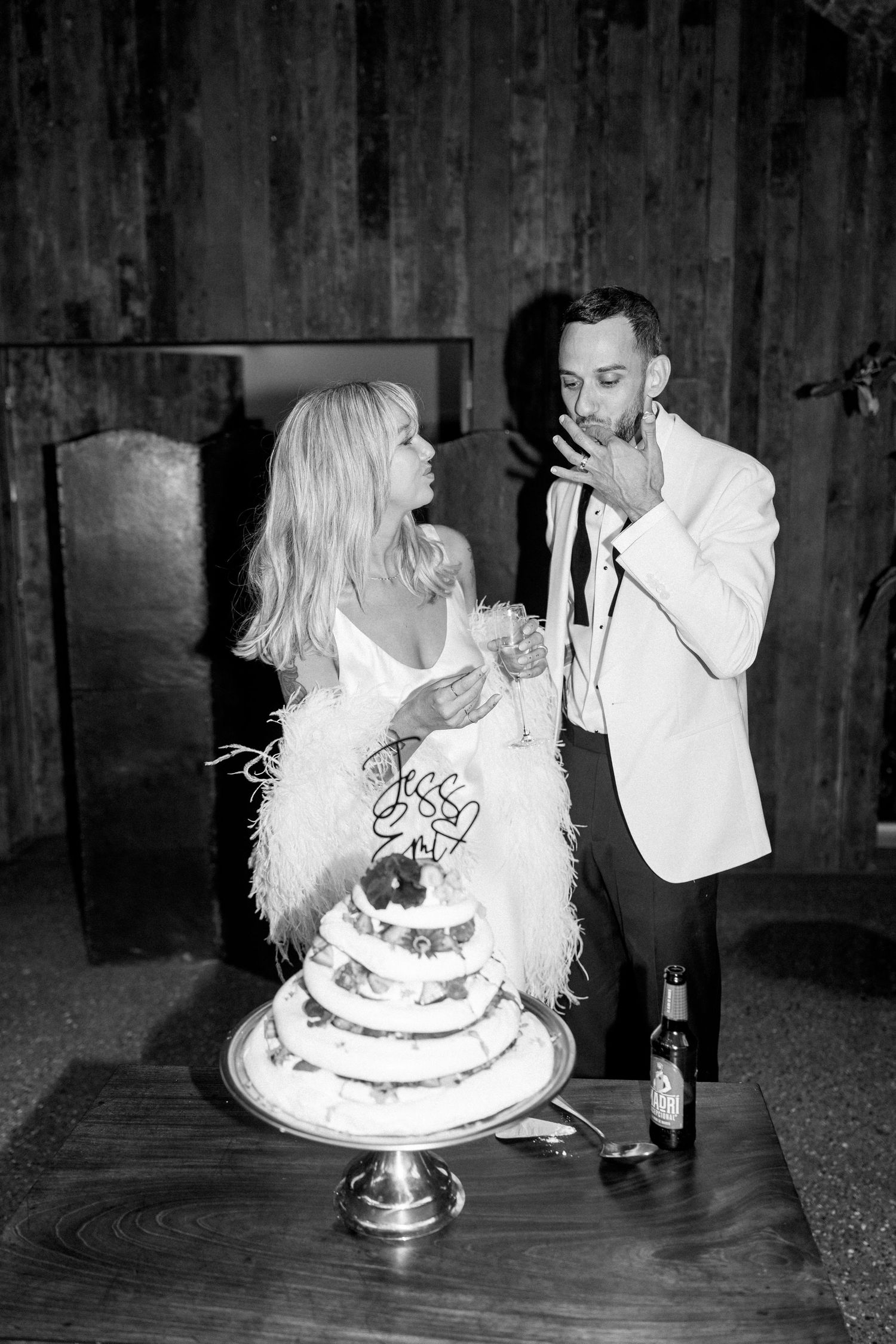 Couple sharing wedding cake in an intimate black and white moment.
