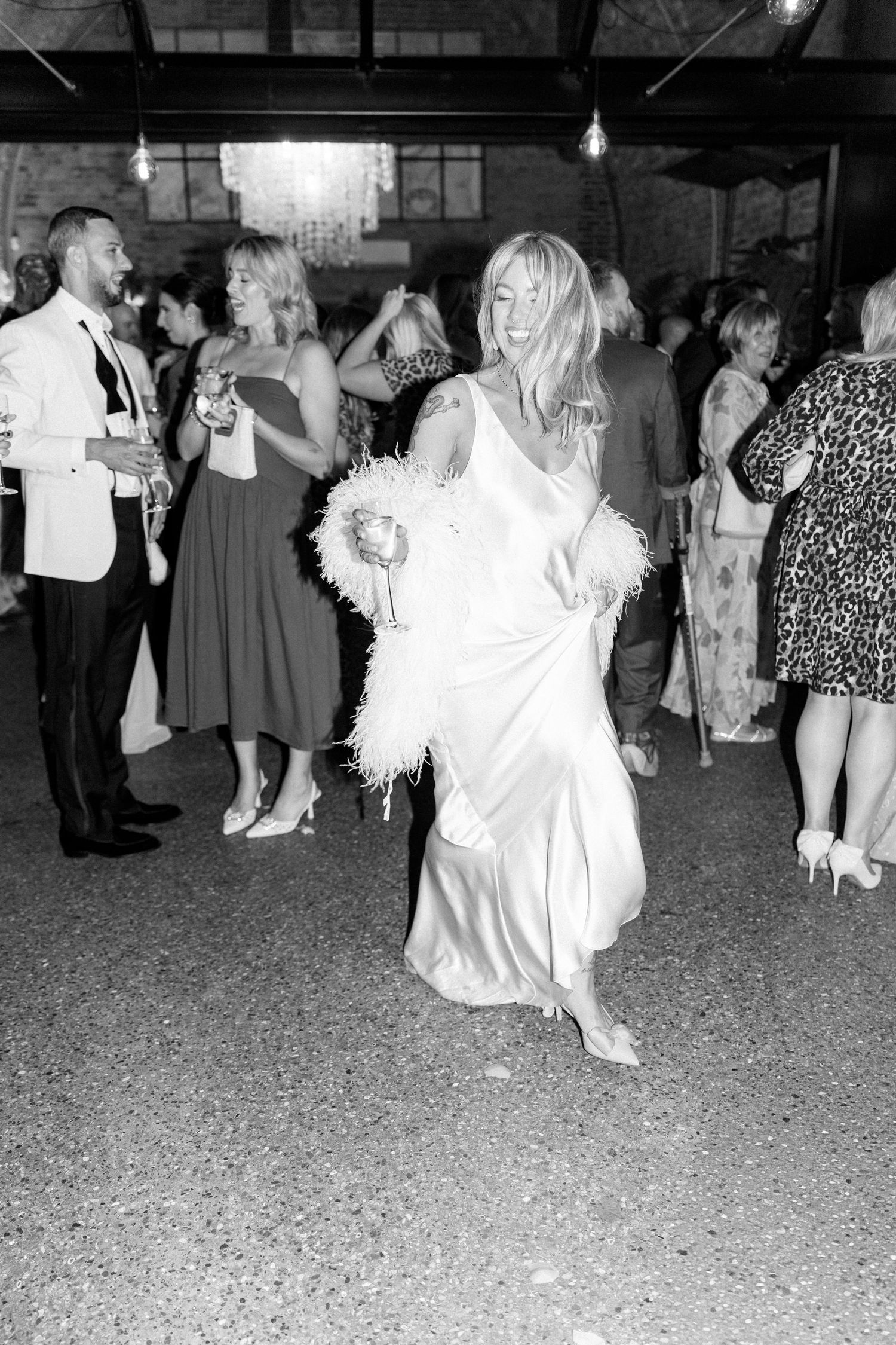 A bride in a silk dress and feather trim dances at her wedding reception.