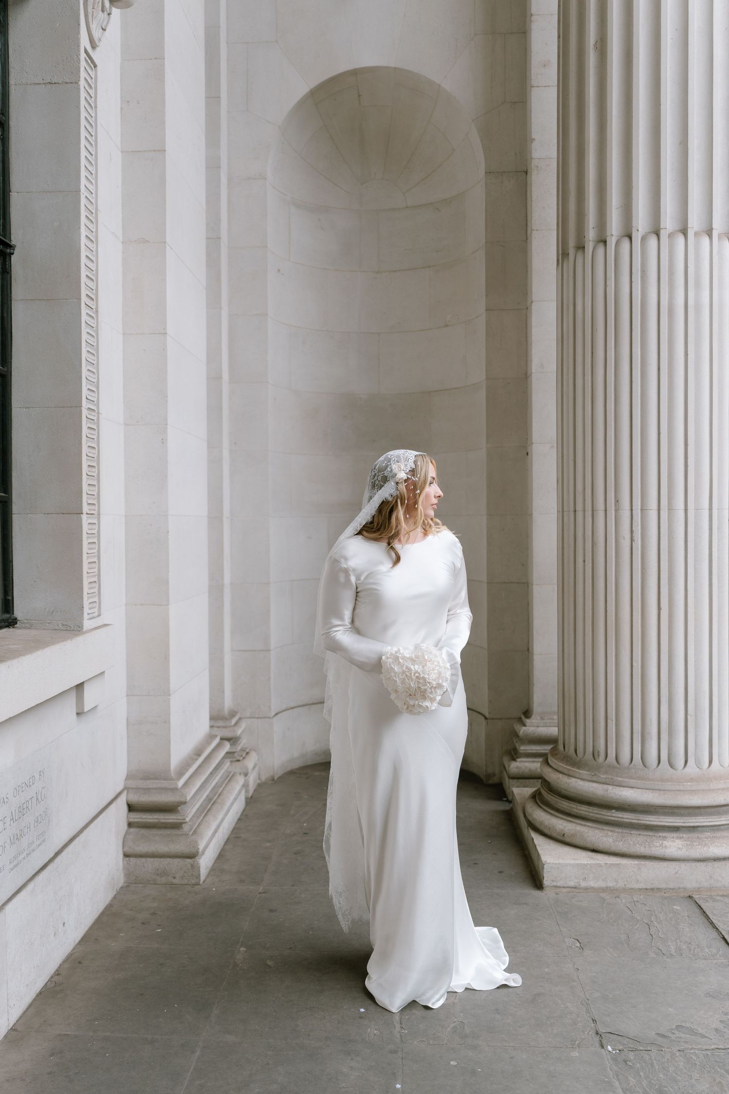 Artistic sequence showing a bride in white dress posing between classical white columns.