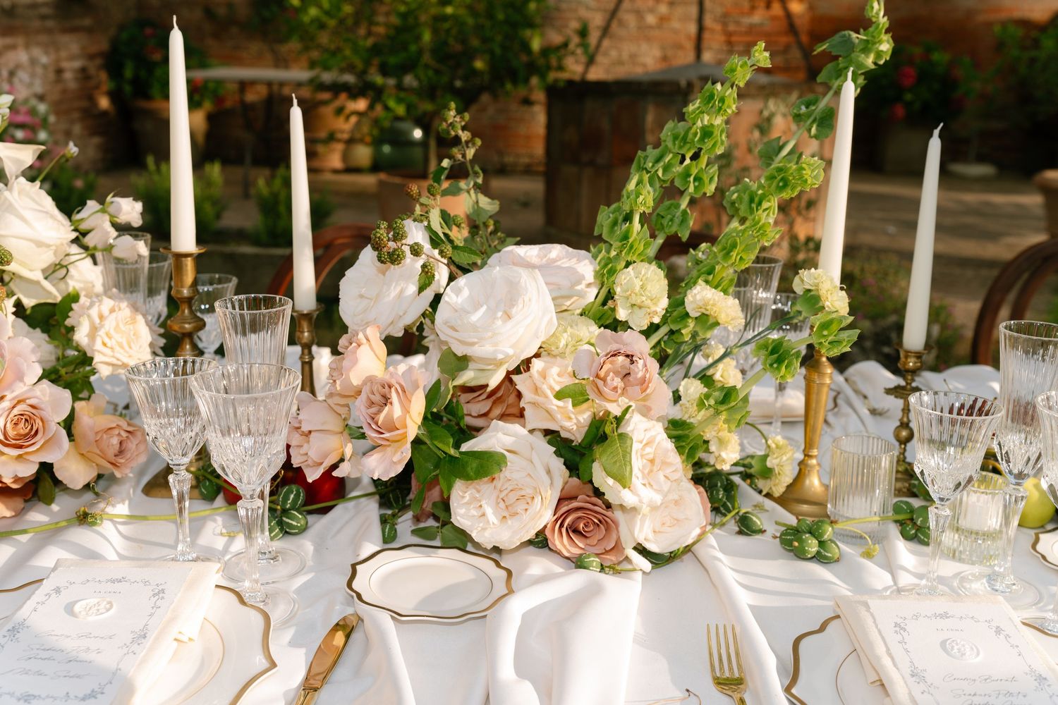 Elegant wedding table setting with pink roses, candles, and crystal glassware.