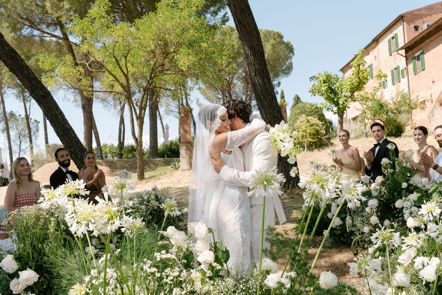 Wedding celebration in a scenic Italian garden with white floral decorations.