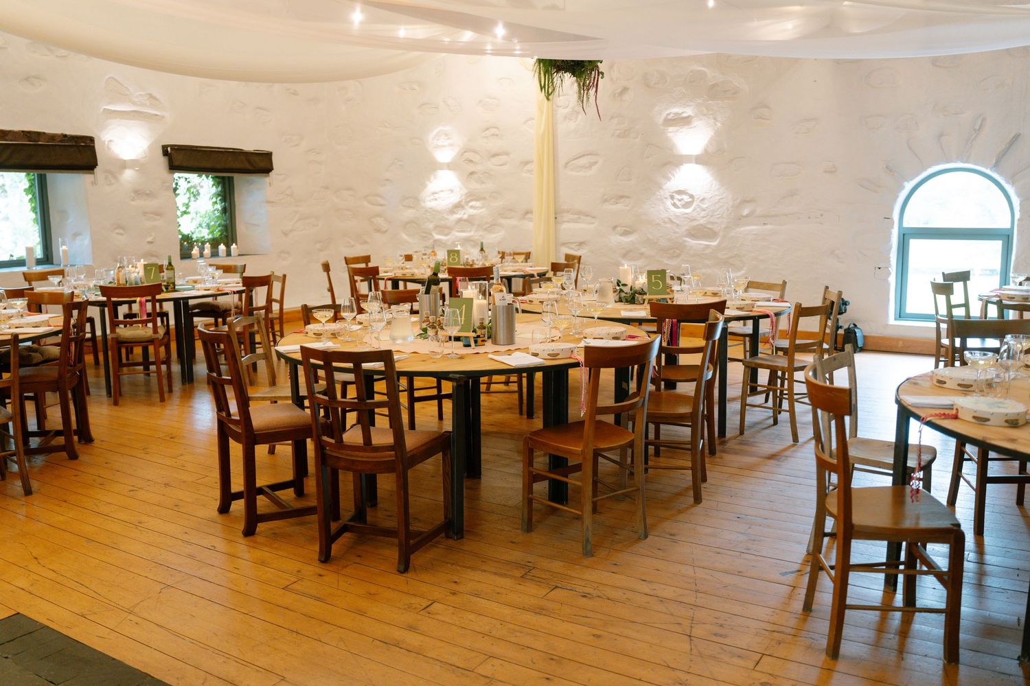 Interior view of an elegant restaurant dining room with wooden tables, chairs and warm lighting.