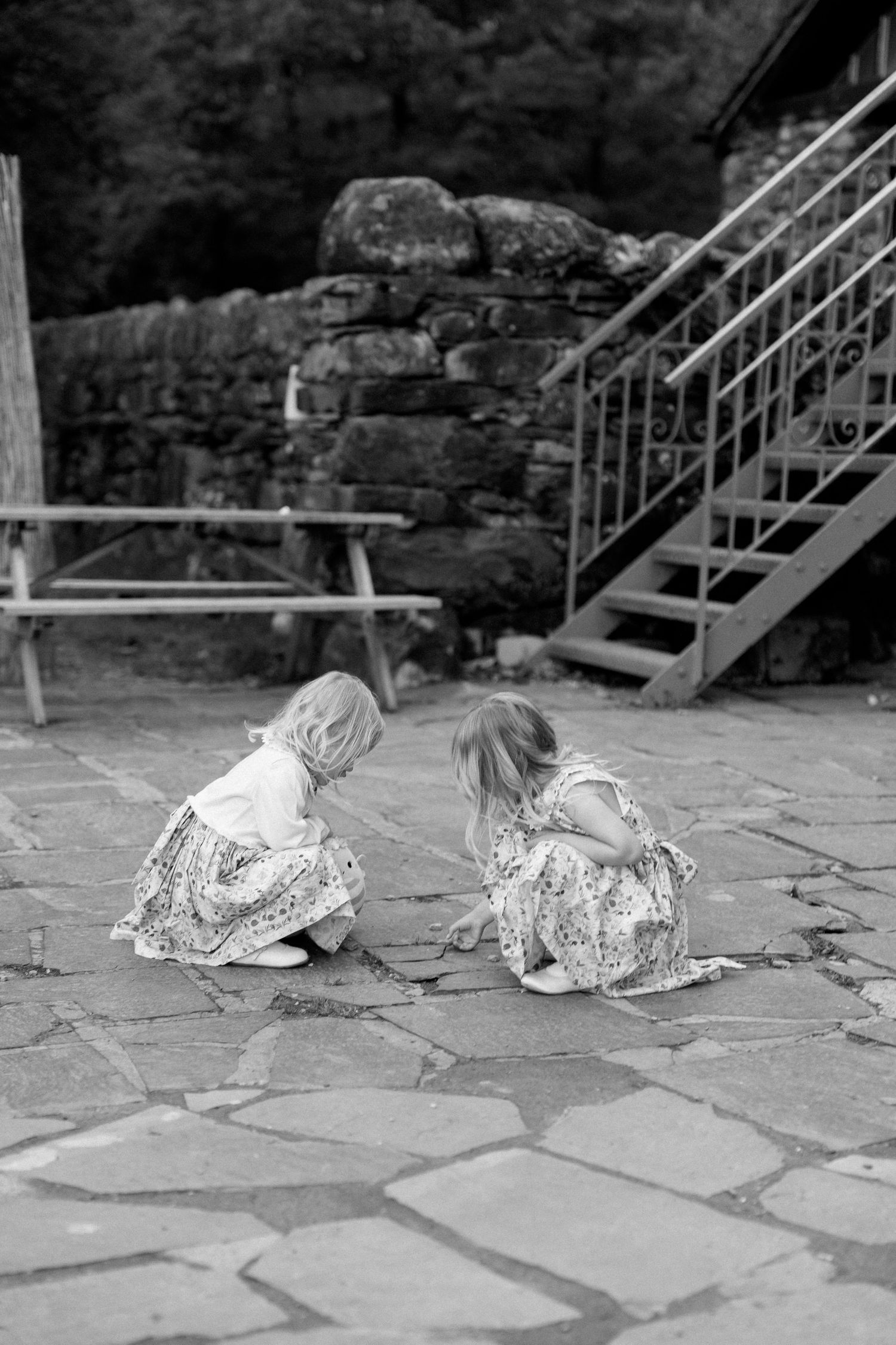 Child in floral dress playing on stone patio during wedding celebration.