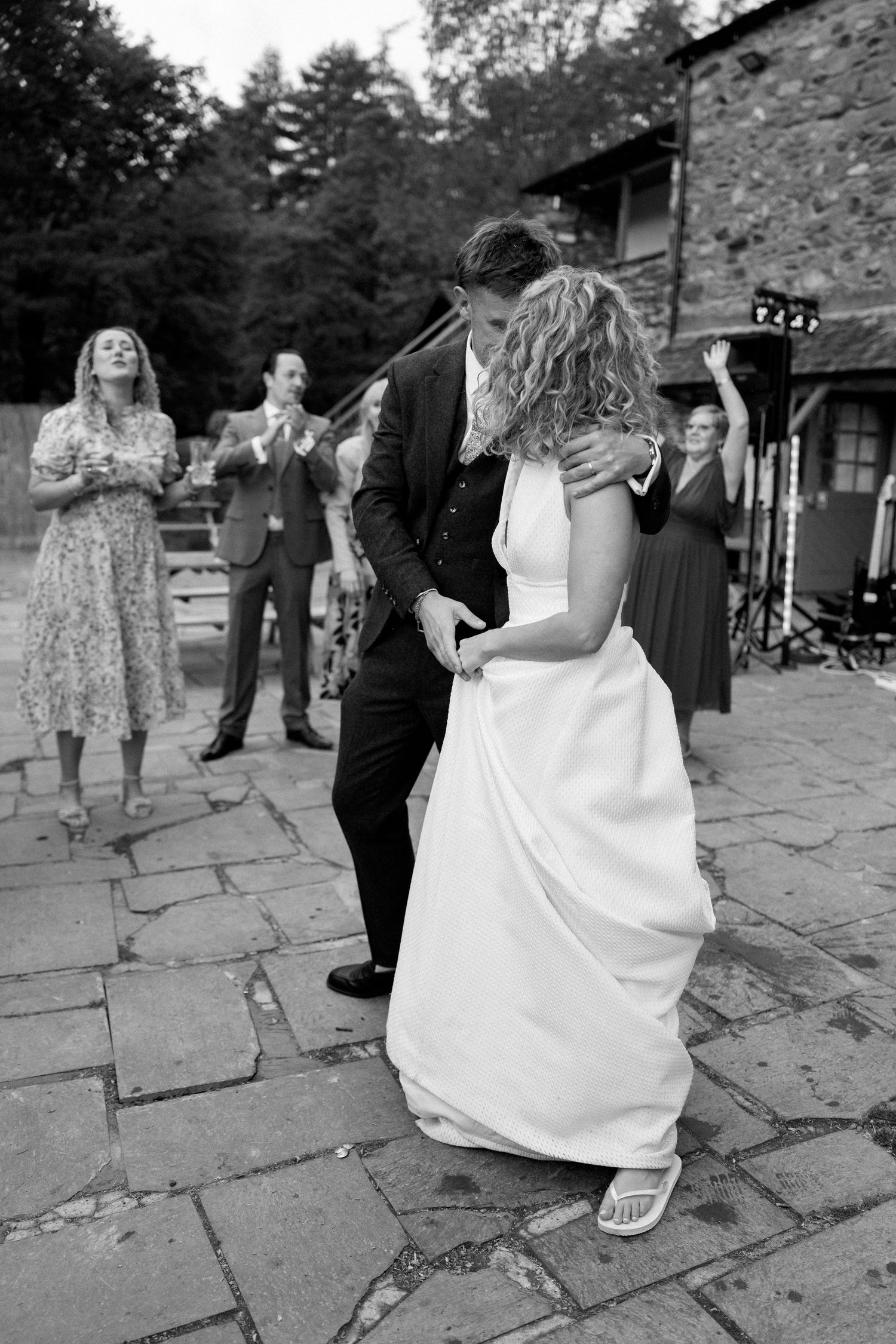 Black and white photos of wedding party dancing on stone patio.