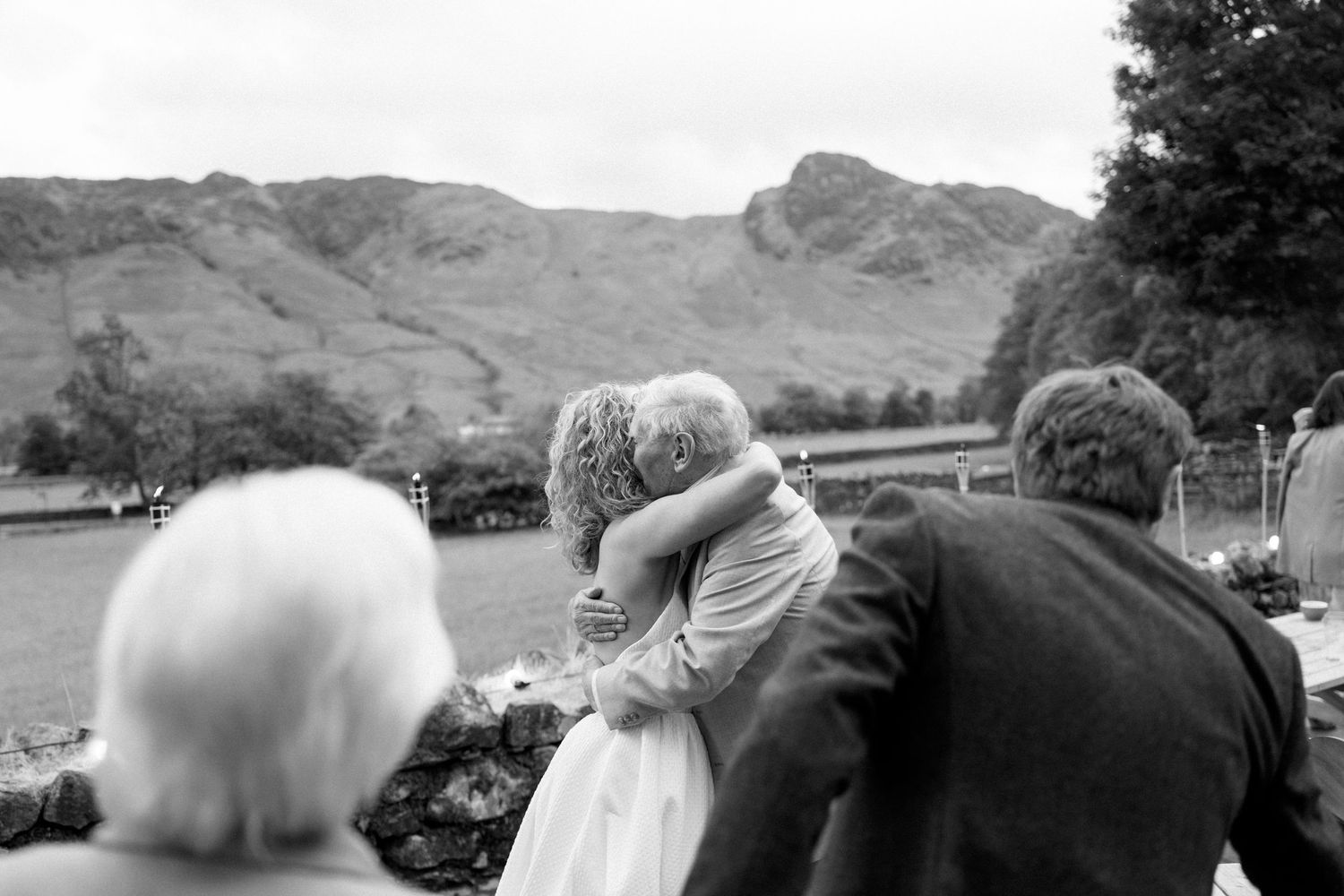 Black and white photo of wedding guests viewing mountain landscape.