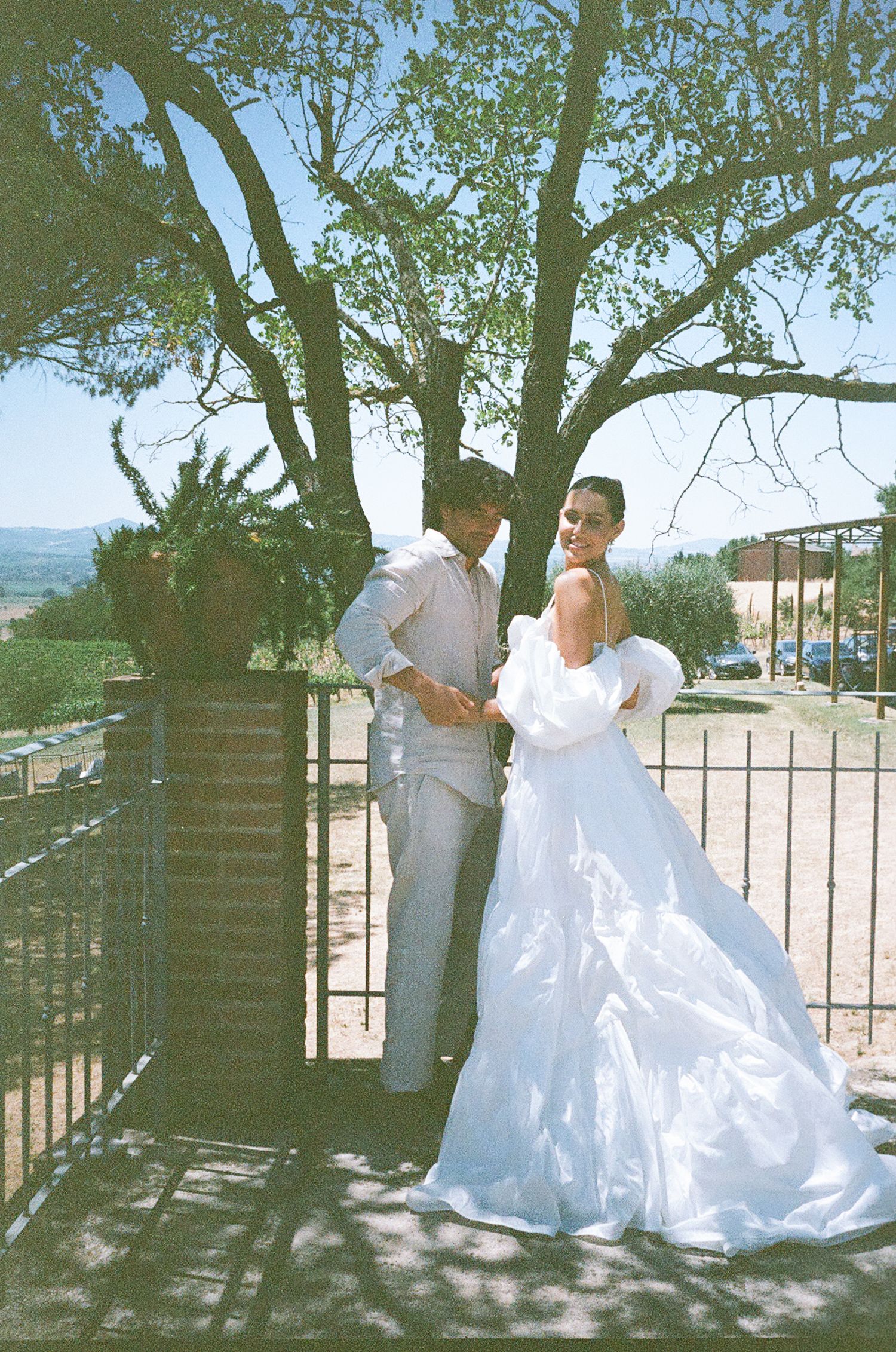 A romantic wedding photoshoot sequence showing a couple in formal attire posing together under a shady tree.