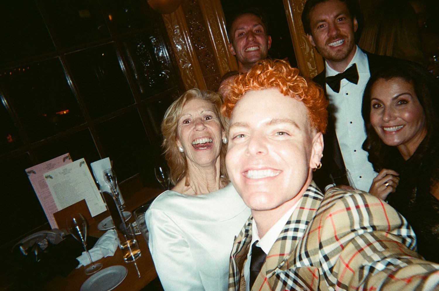 Group of friends laughing and having fun together at a dimly lit party or social gathering.