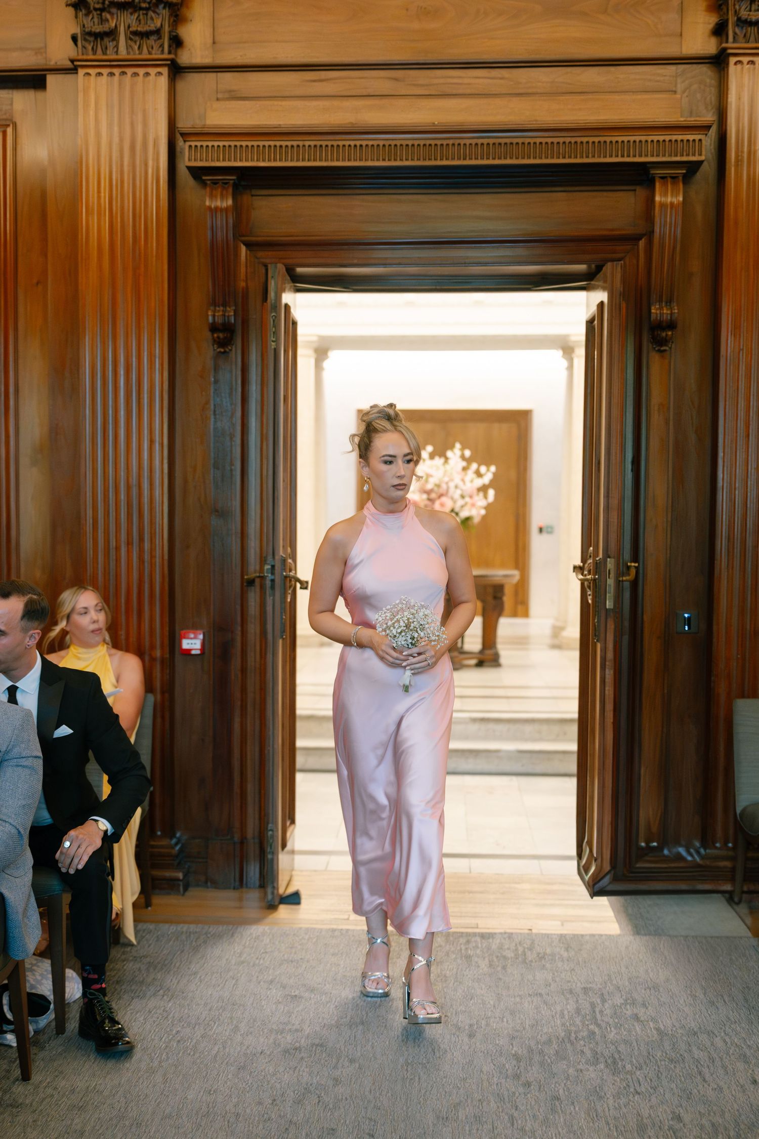 Formal event attendees entering through wood-paneled doorway.