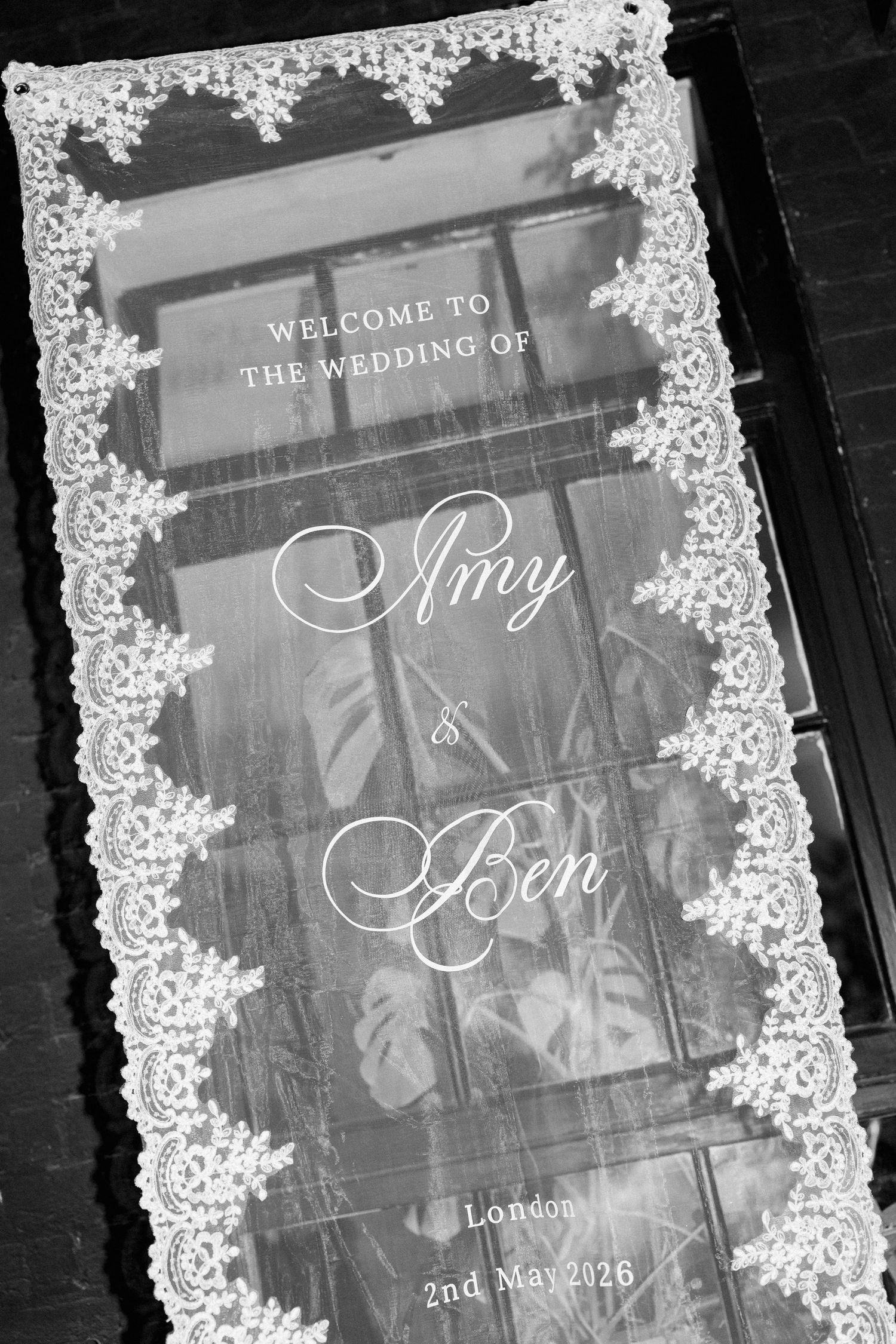 Black and white welcome sign for Amy and Ben's London wedding on 2nd May 2026 with lace border decoration.