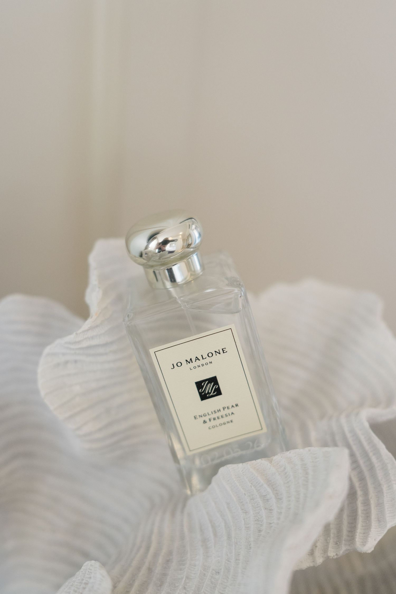 Jo Malone London English Pear & Freesia cologne bottle on white fabric.