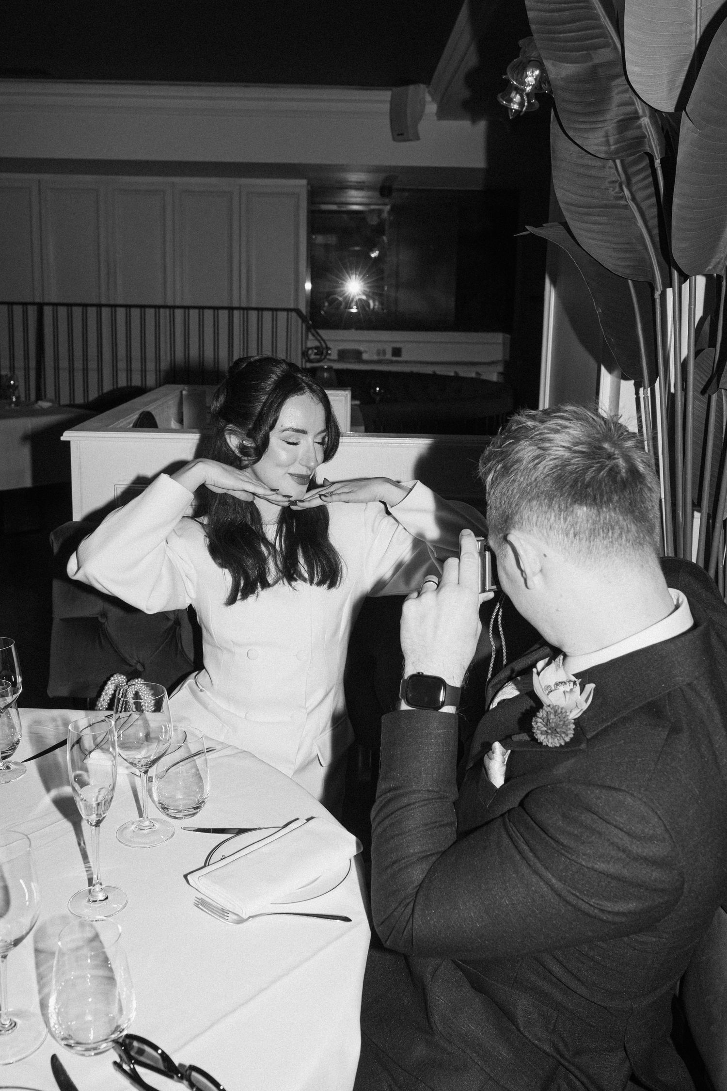Bride and groom at wedding reception dinner table in black and white photography.