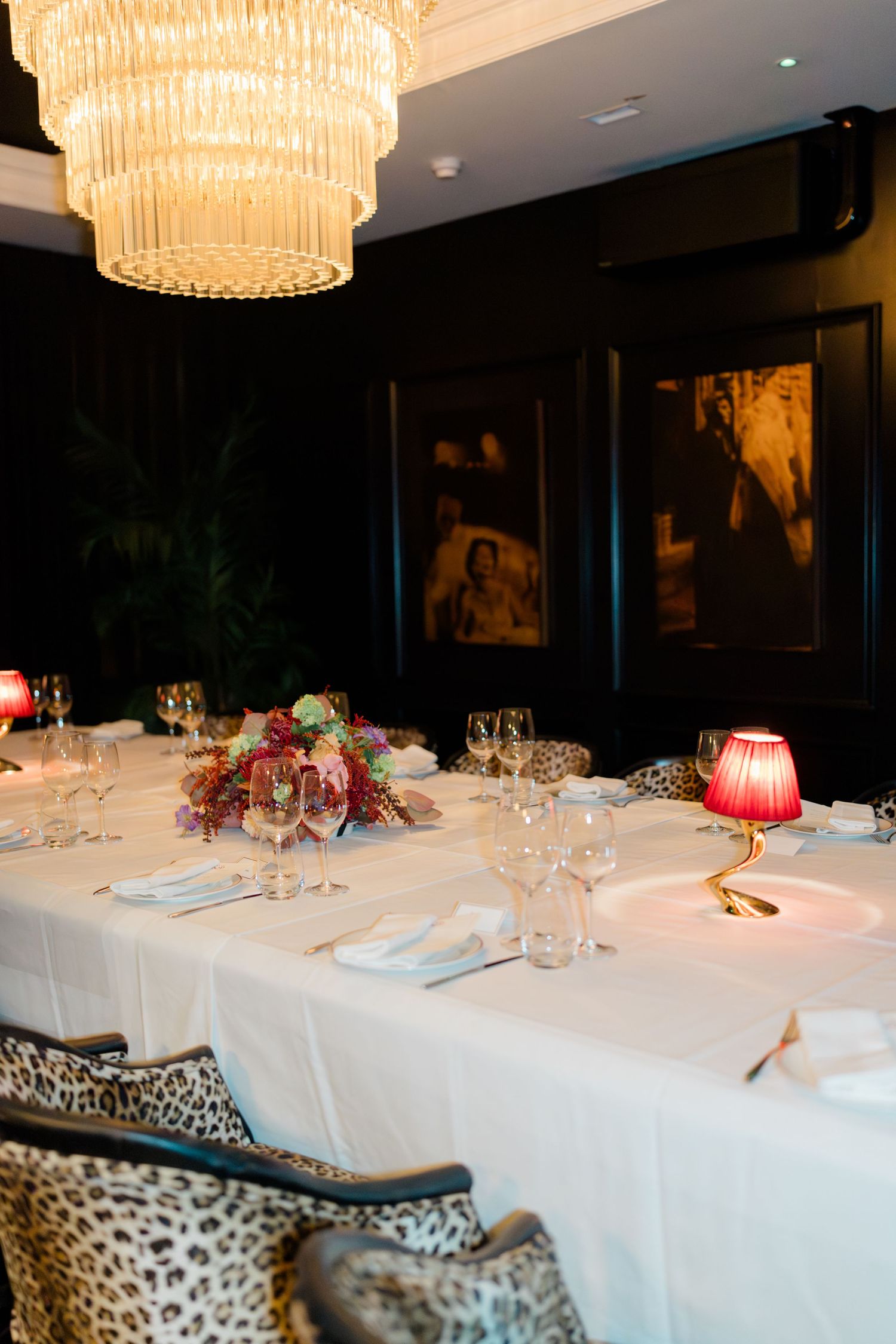 Elegant wedding reception table with crystal chandelier, floral centerpiece, and candles.