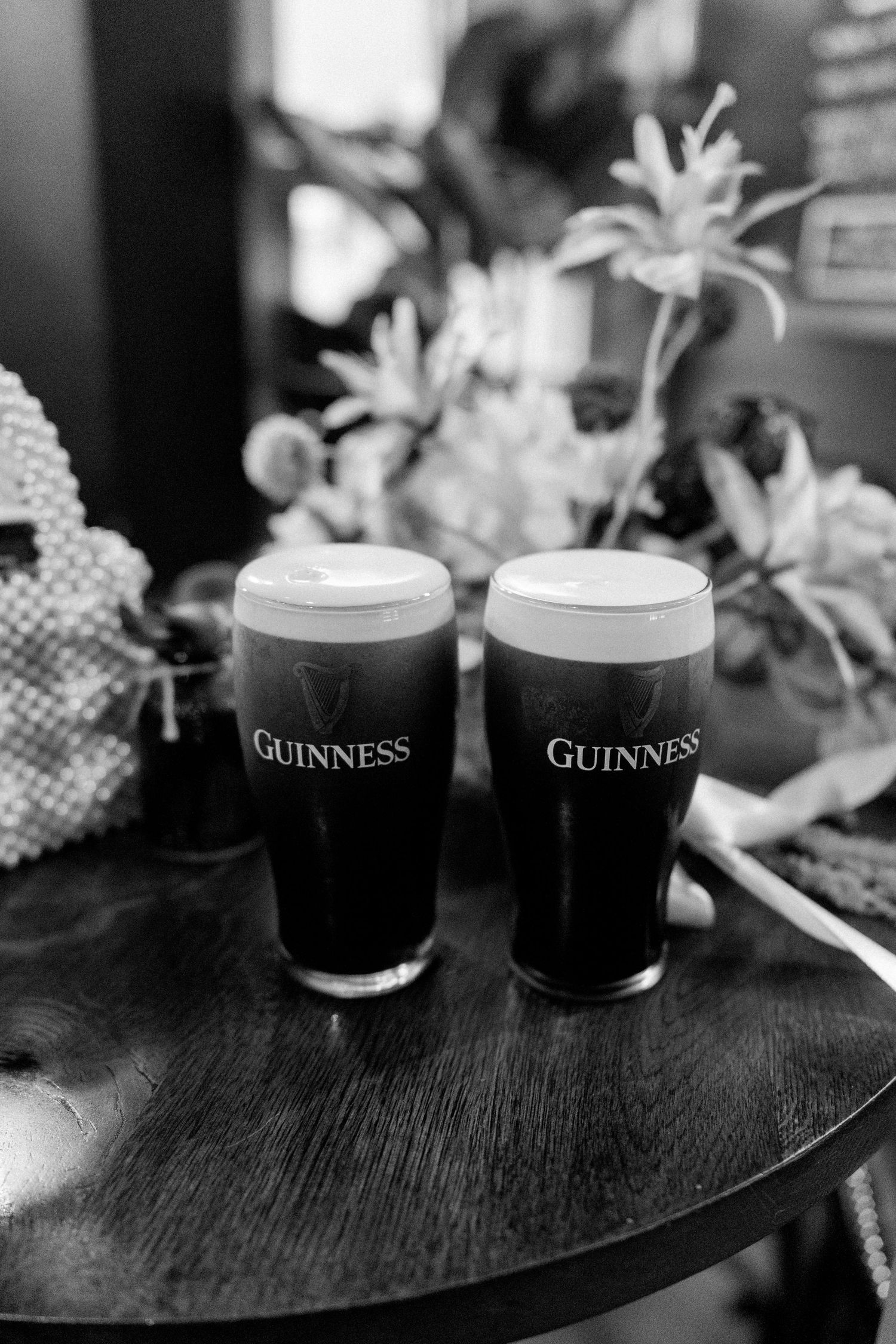 Two pints of Guinness stout sit on a dark wooden table at a pub wedding celebration.