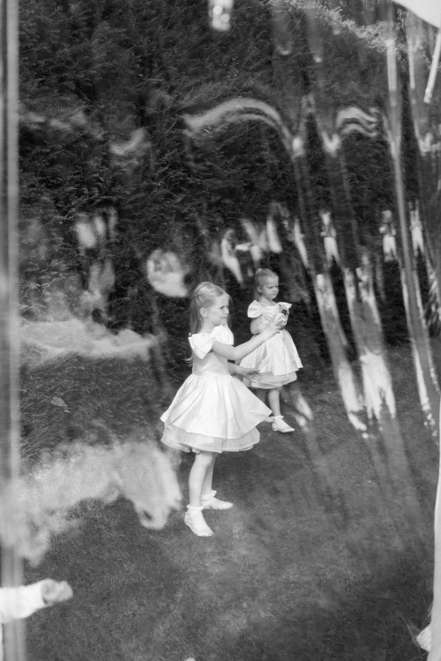 Vintage black and white photograph showing people dancing outdoors among trees.