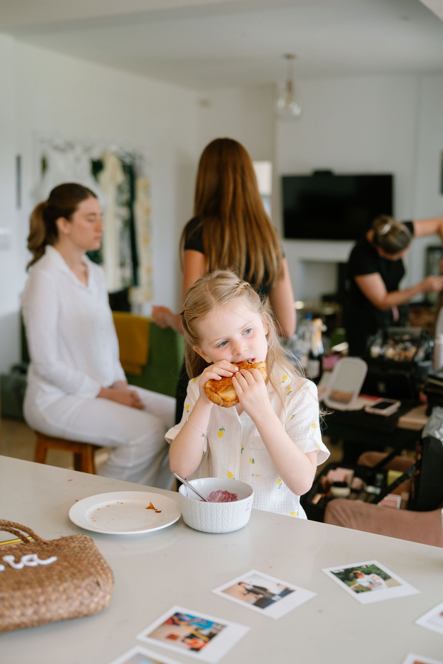 Child enjoying food at white table with photographs displayed.
