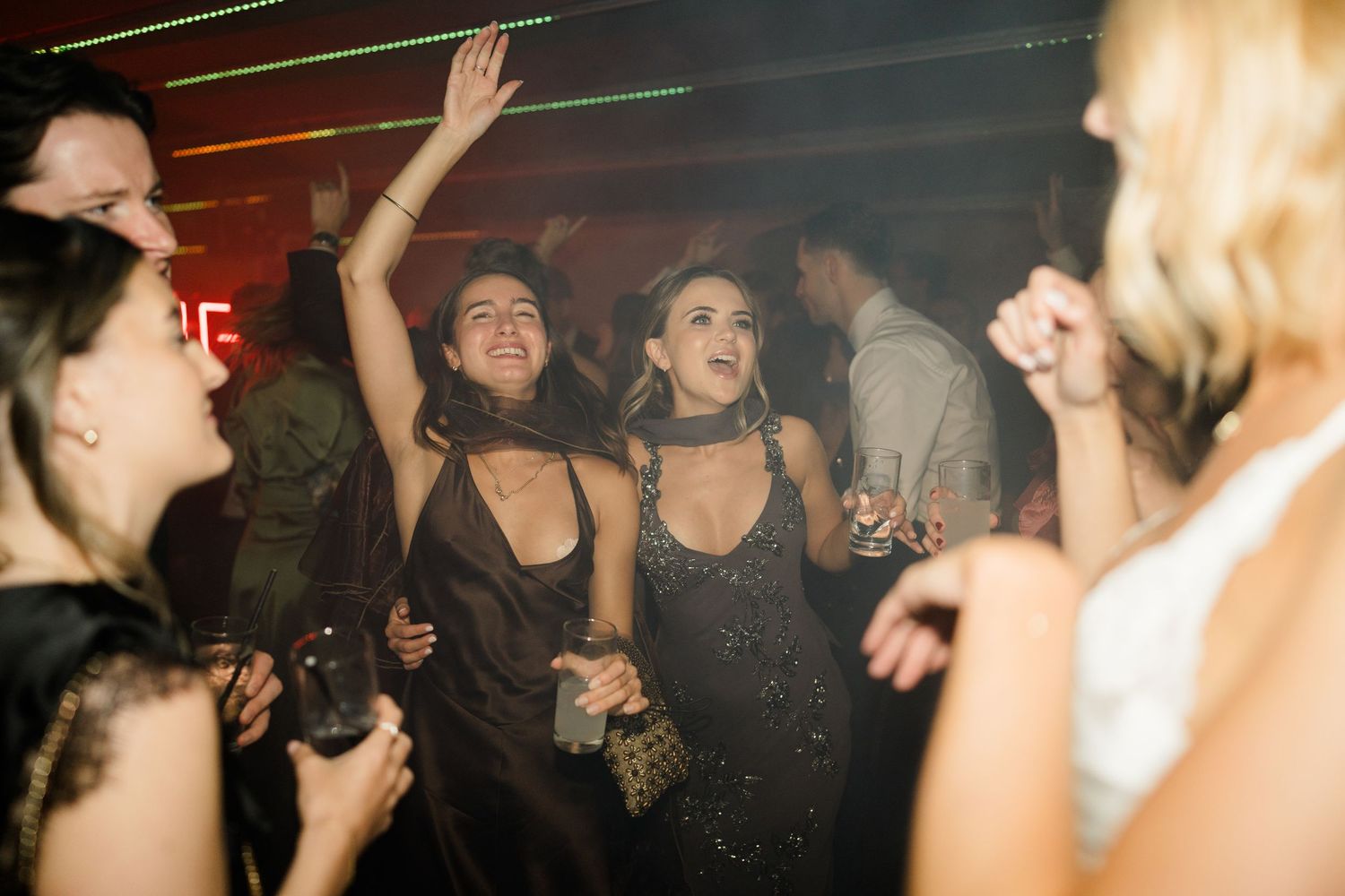 Guests in elegant evening wear dance and celebrate at a lively wedding reception party.