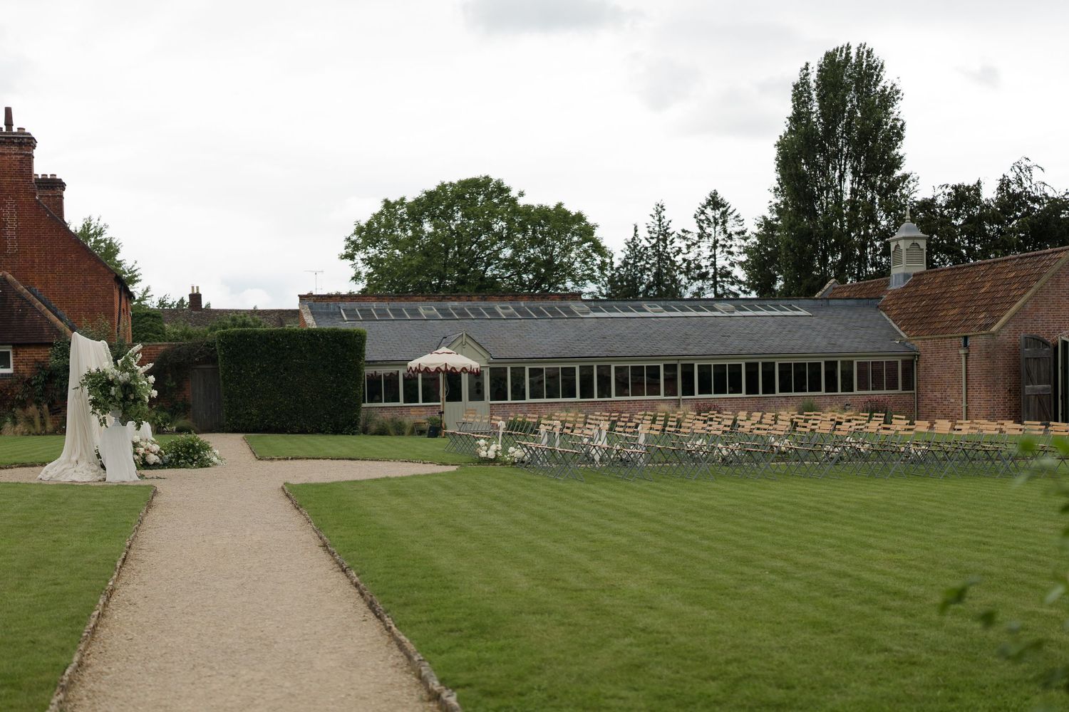 Elegant English manor wedding venue with a glass greenhouse reception hall surrounded by manicured lawns.