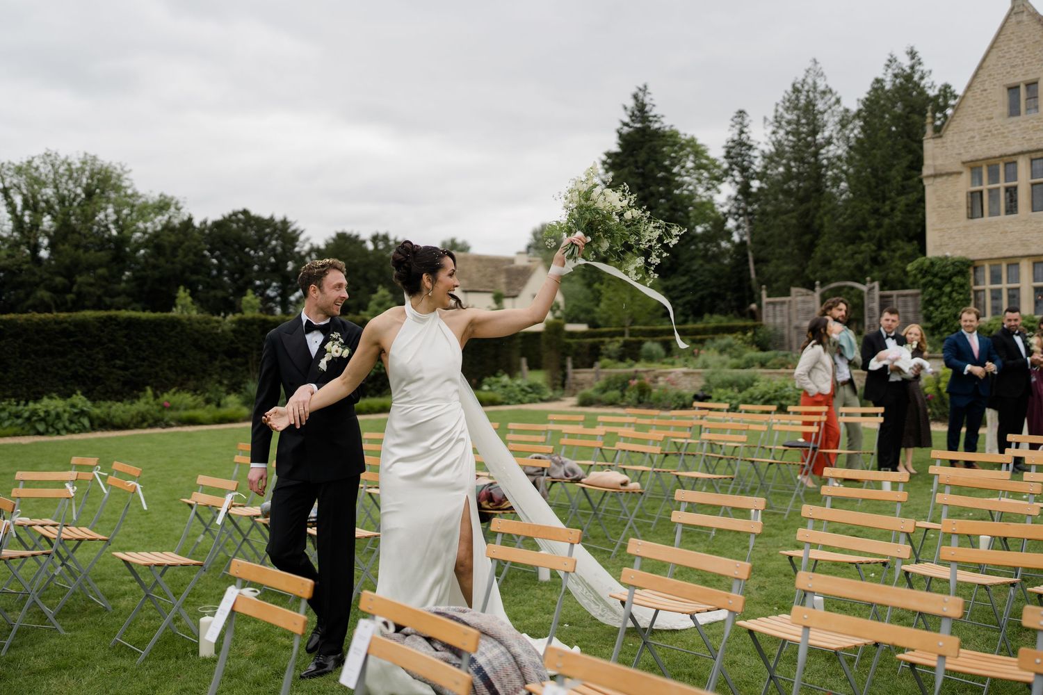 Bride and groom celebrate after outdoor garden wedding ceremony at historic manor.